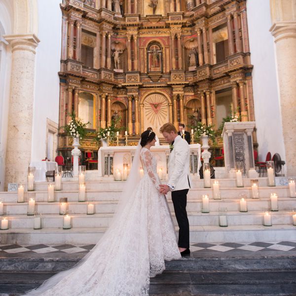 Bride and groom holding hands at candle-filled altar during catholic wedding ceremony