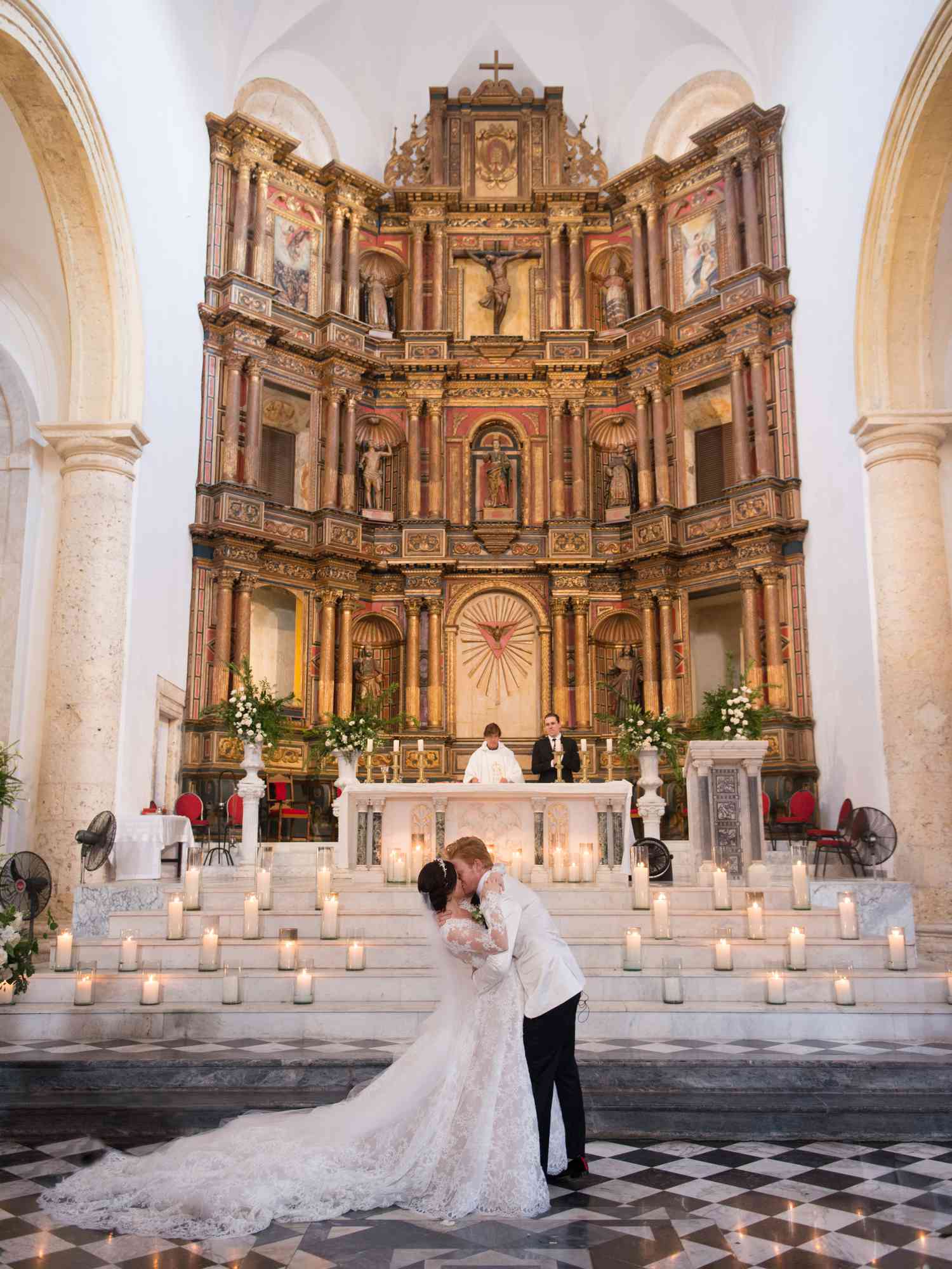 Bride and Groom Sharing First Kiss During Christian Wedding Ceremony Pronouncement in Candle-Decorated Church