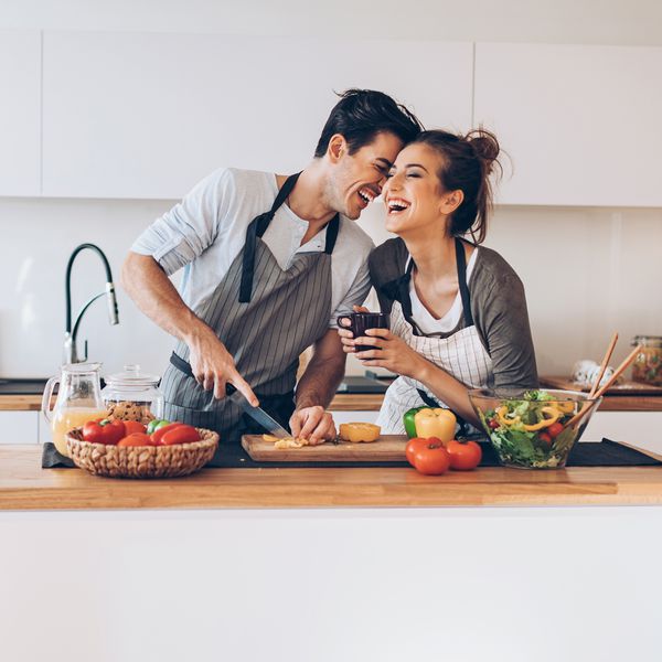 Affectionate couple preparing salad in a domestic kitchen