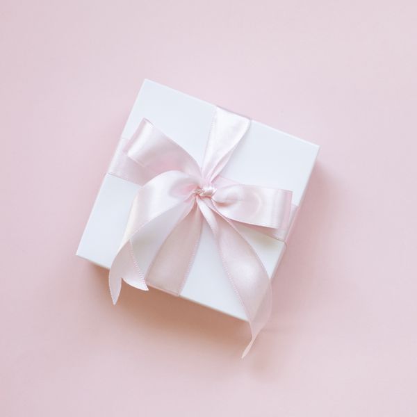 A gift box with pink ribbon on a pink background