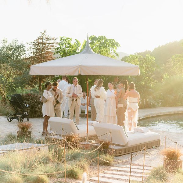 Guests standing near a pool in light-hued clothing during wedding cocktail hour