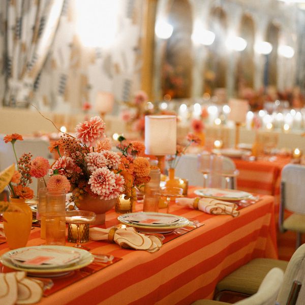 Verona Sunset Tablescape With Striped Orange Linens, Pink and Orange Dahlia Centerpieces, Small Lamps, and Acrylic Placemats