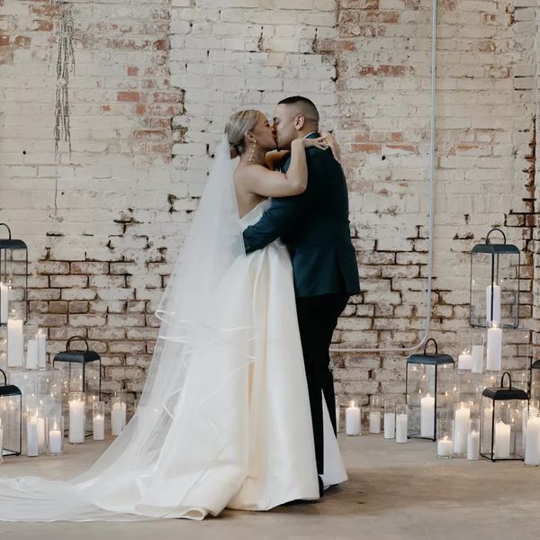 Bride and groom kissing at the altar surrounded by white candles
