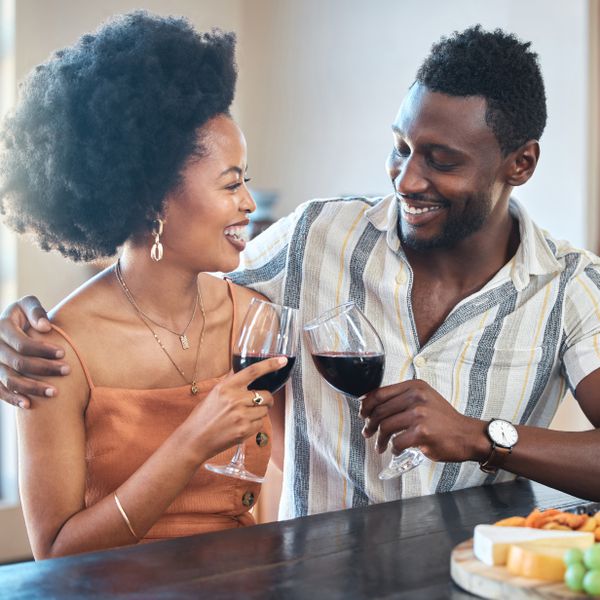 Young couple celebrating with wine and cheers at resort, laugh and bonding on romantic date