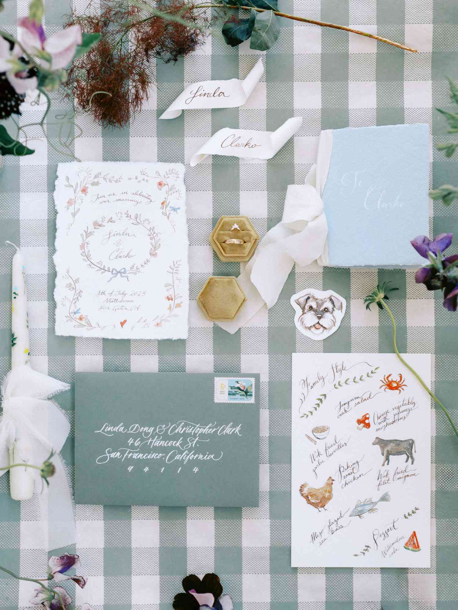 Sage Green Whimsical Wedding Invitations Next to Rings and Purple Flower Decor