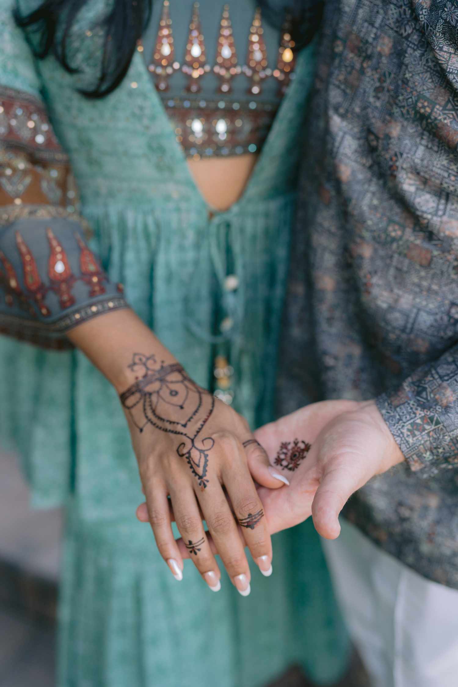 Close up of bride in green Indian dress with french nails and groom with henna on hands