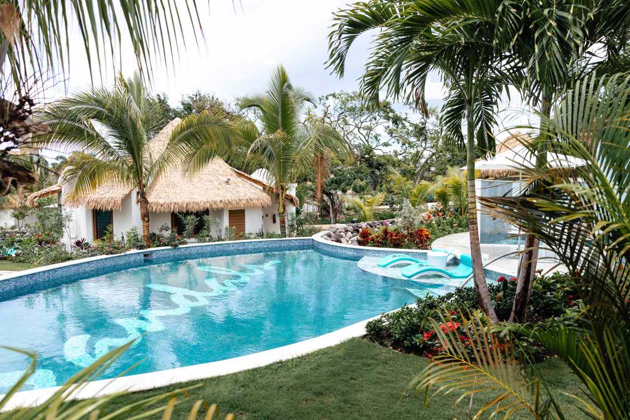 Pool Surrounded by Modern Huts and Palm Trees at Wedding Venue