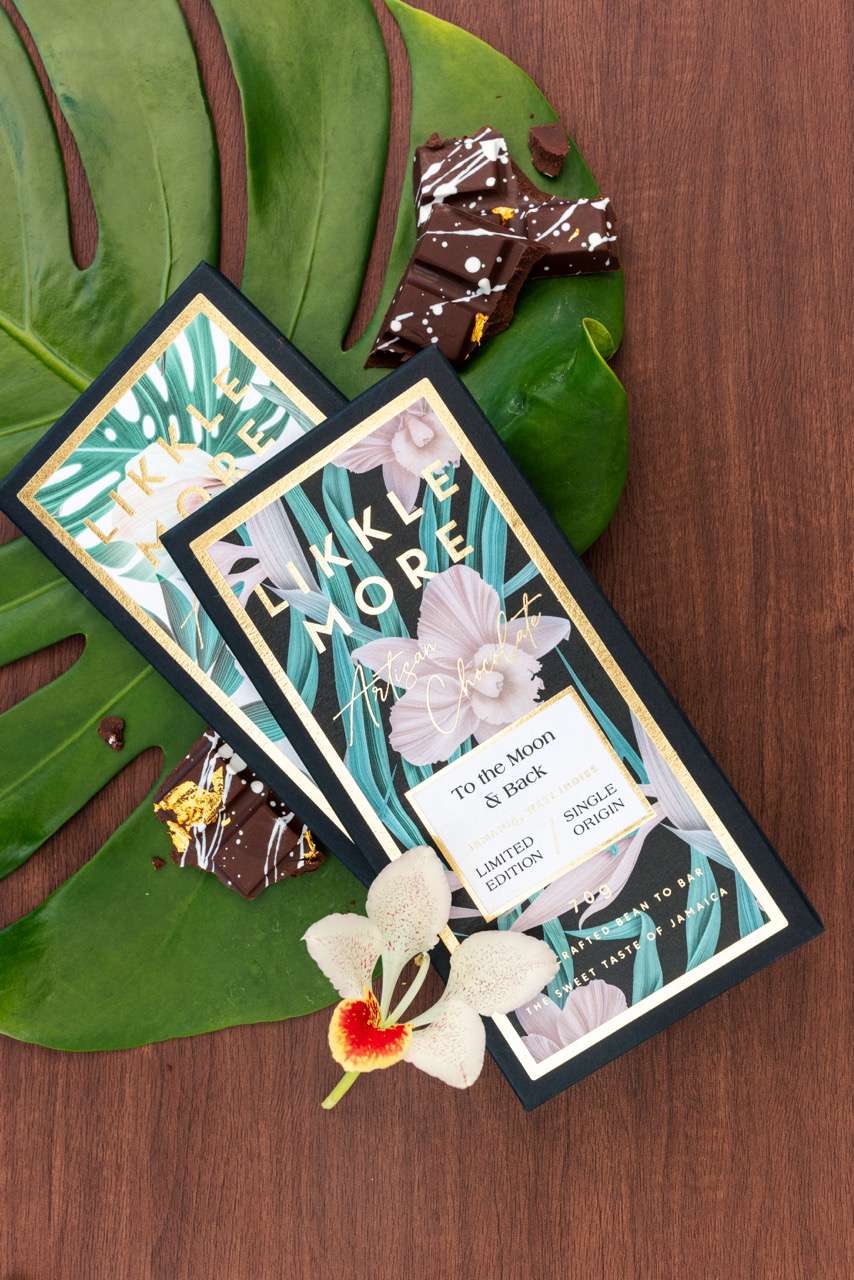 Close Up of Chocolate Bar Packaging Next to Chocolate Pieces on Monstera Leaf