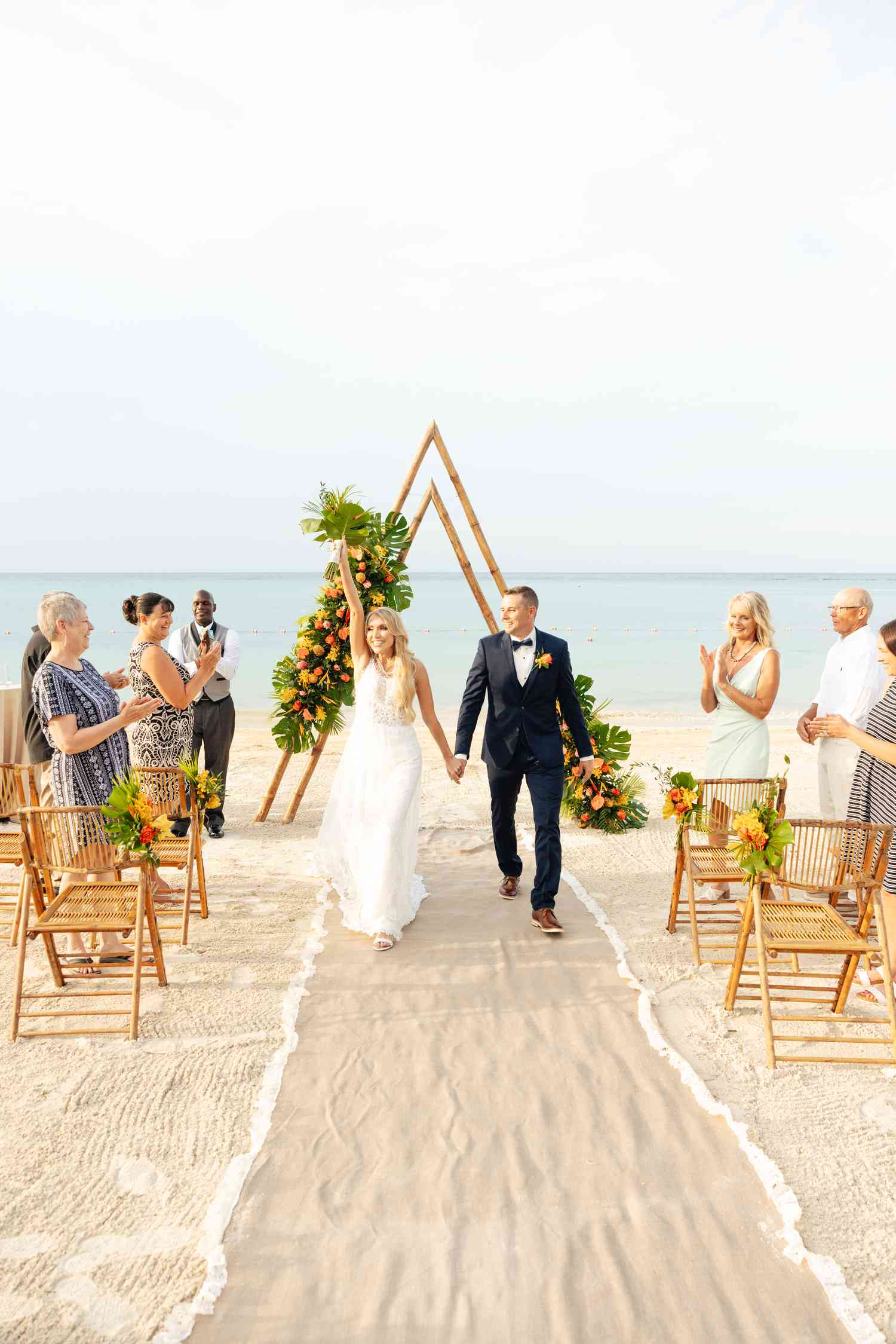 Bride in White Wedding Dress Walking Down Aisle With Groom in Tuxedo at Beach Wedding