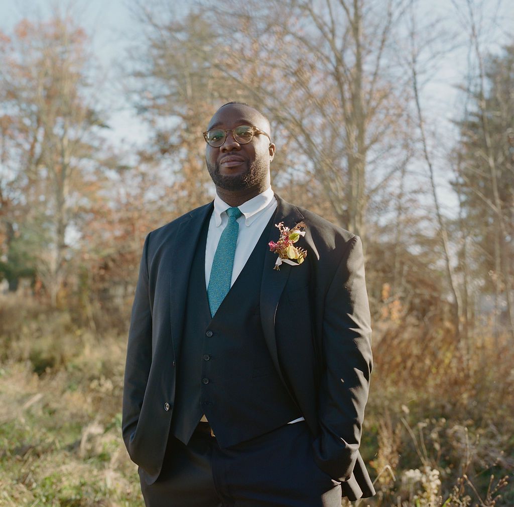 Portrait of Groom in Black Suit With Teal Tie Posing in Front of Woods