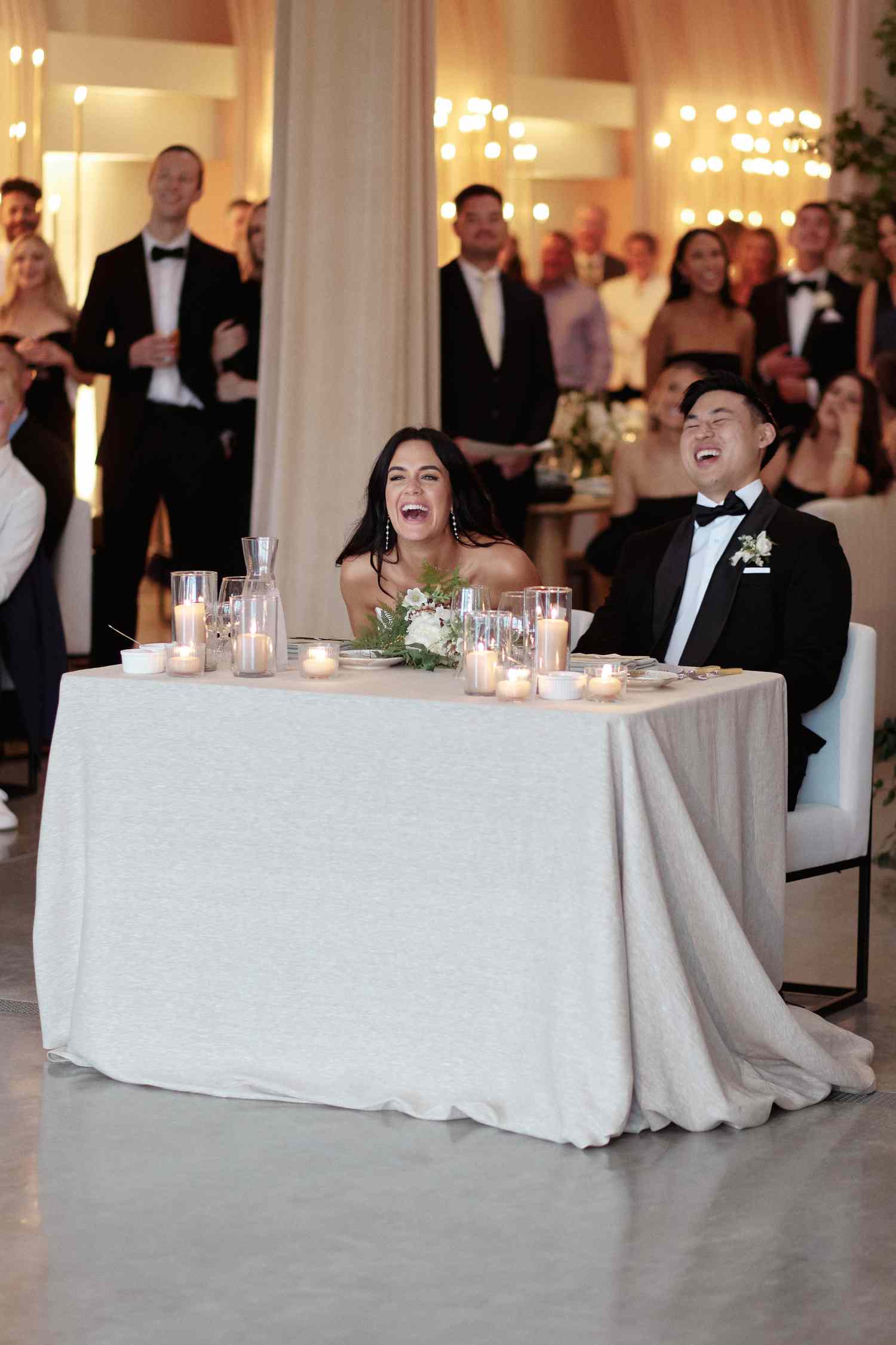 Bride and Groom Laugh at Their Reception While Listening to a Wedding Speech