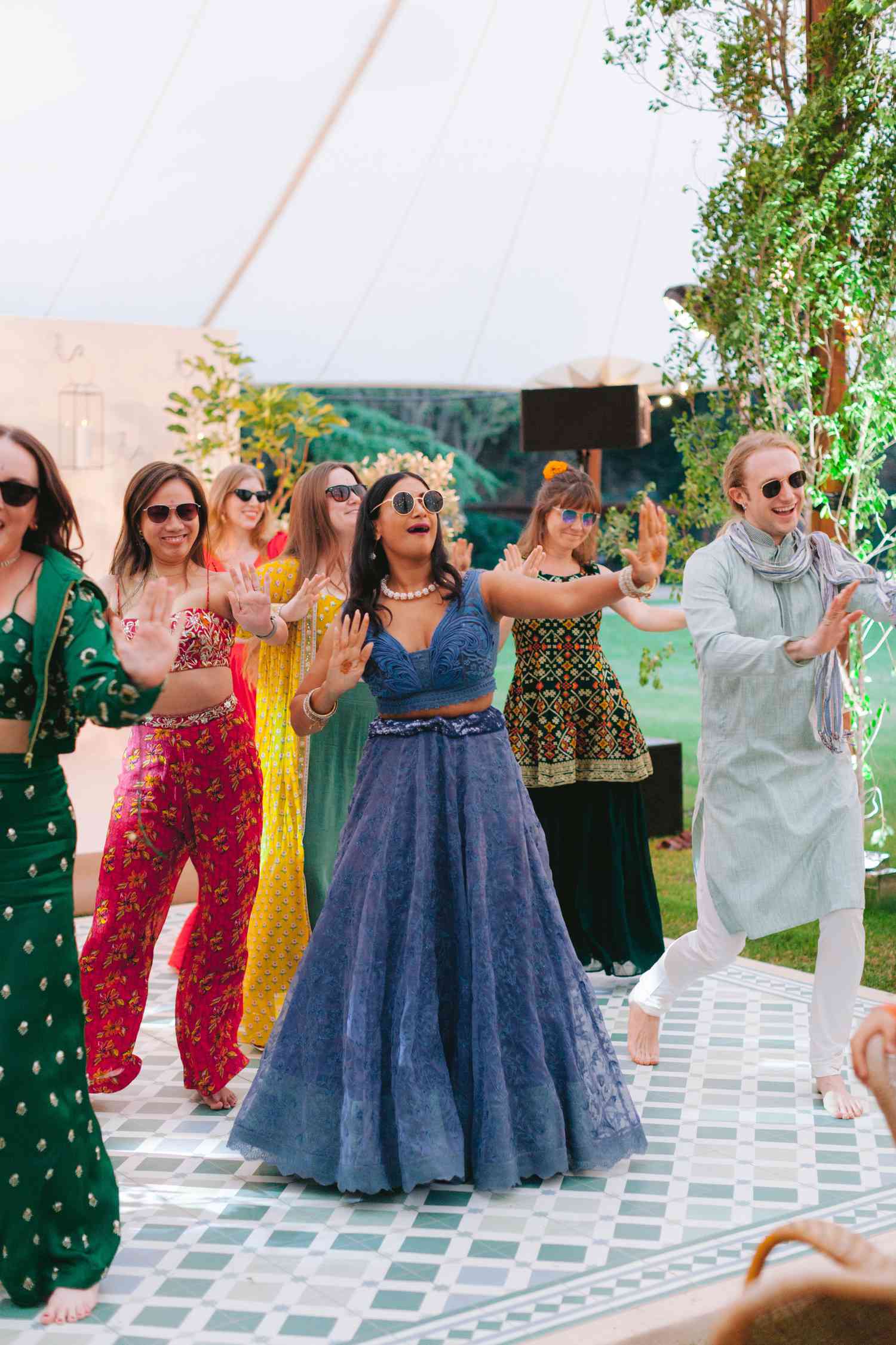Wedding guests in bright and colorful Indian attire dancing at sangeet