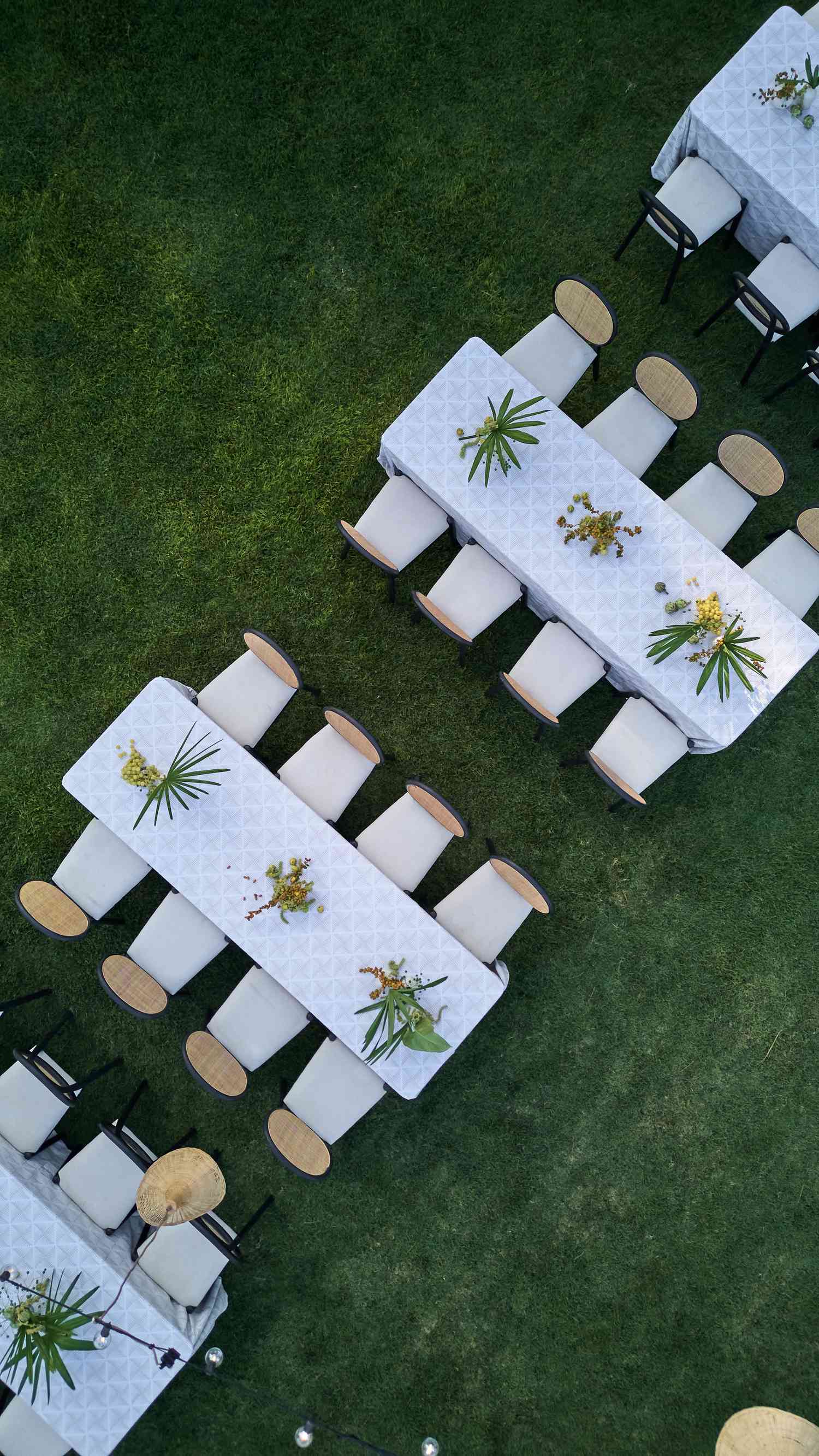 Aerial View of Small White Tables With Plant Decor and White Chairs on Grass