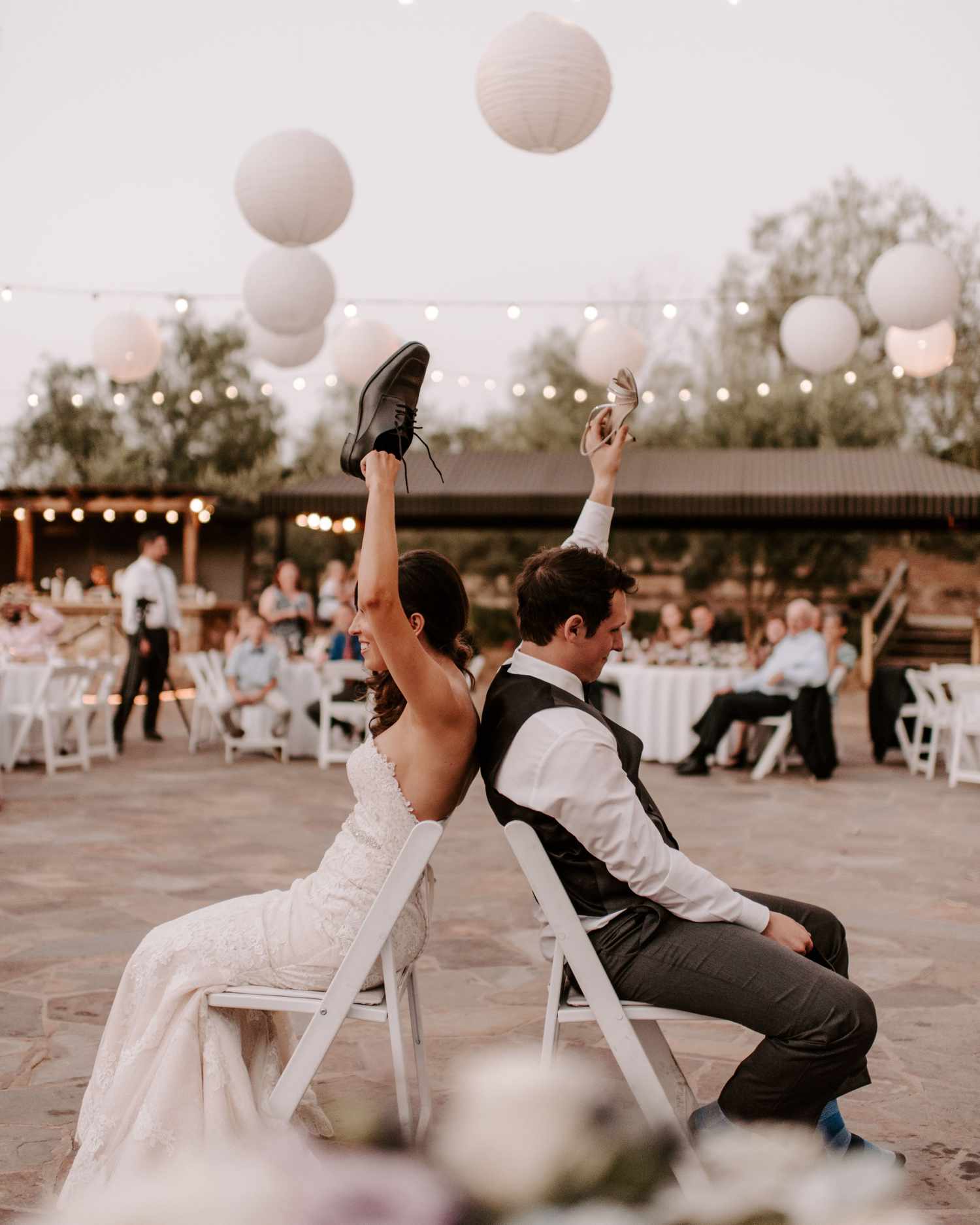 A bride and groom seated on the dance floor holding shoes during the Wedding Shoe Game.