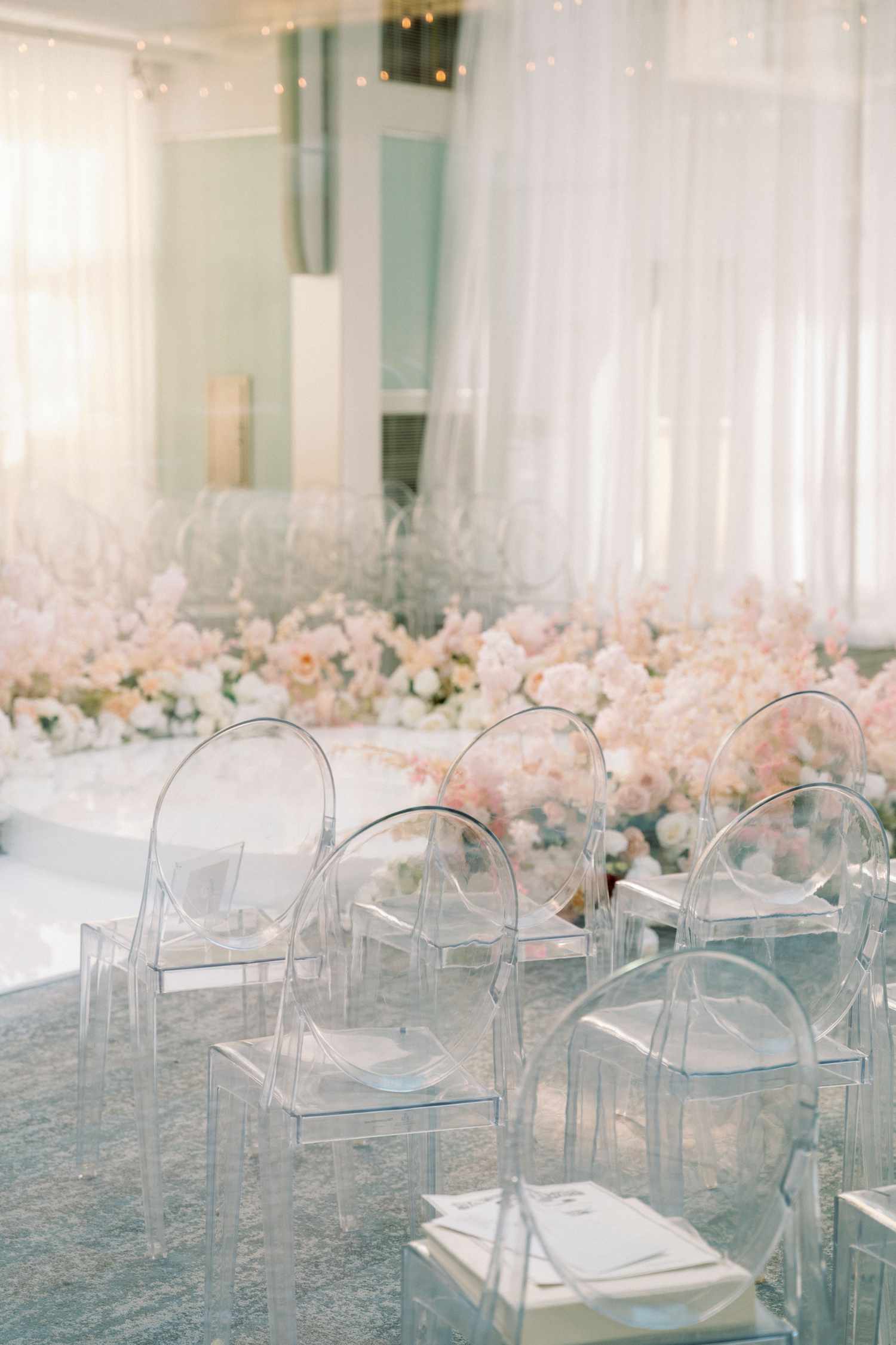 clear chairs in a row in front a floor filled with flowers