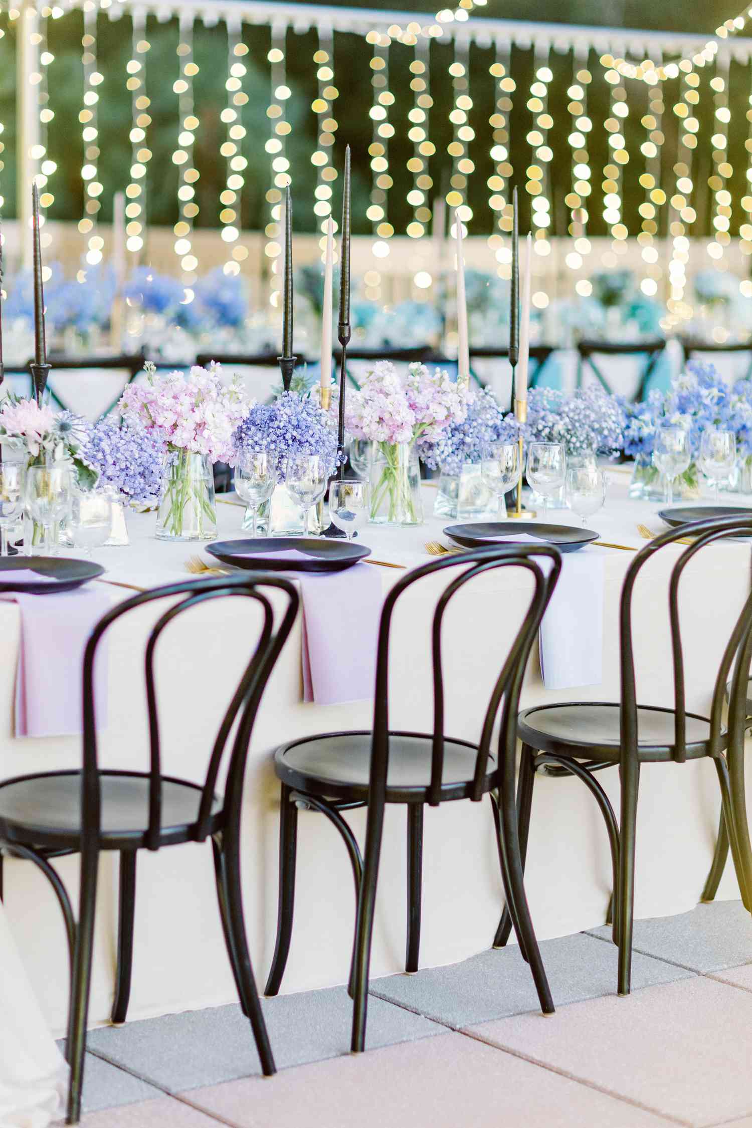 Purple Flower Decor Next to Purple Table Setting on White Table at Wedding Reception
