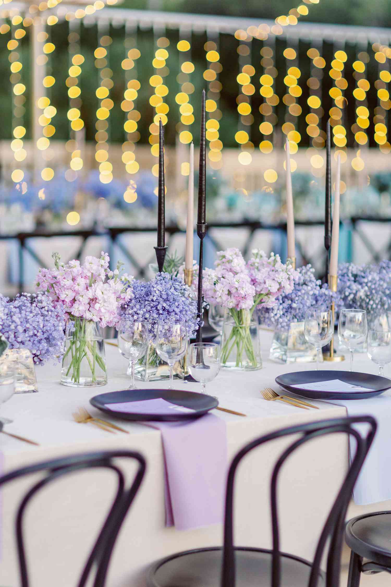 Purple Flower Decor Next to Purple Table Setting on White Table at Wedding Reception