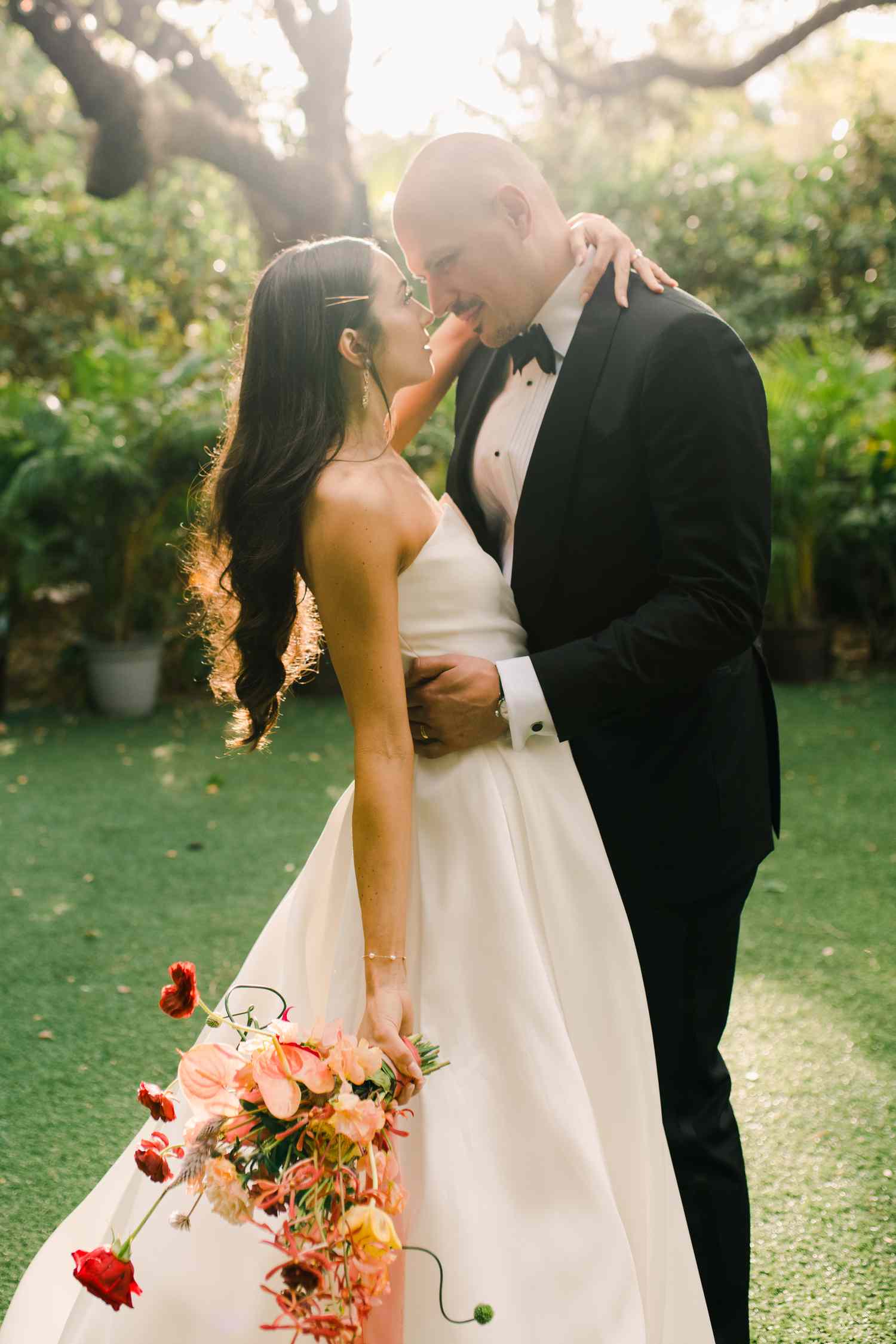 Bride in Wedding Dress With Hair Down Hugging Groom in Black Tuxedo