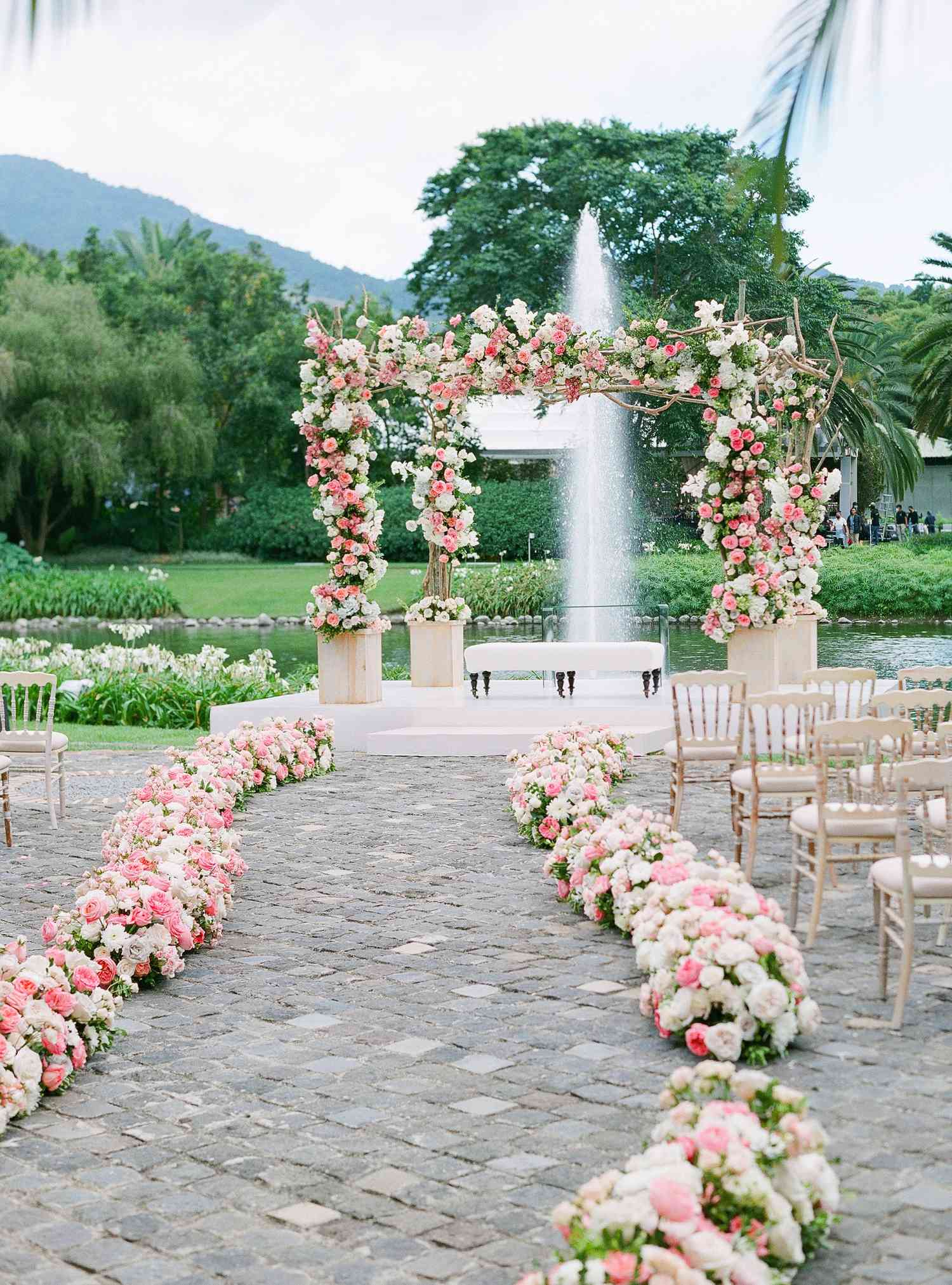 A wedding aisle path with pink and white florals leading to an arch.