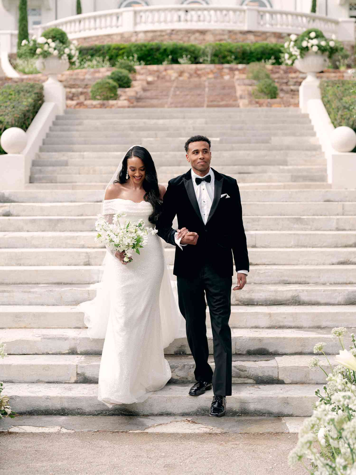 Bride in Off-the-Shoulder Wedding Dress and Brother in Black Tuxedo Walking Down Stairs