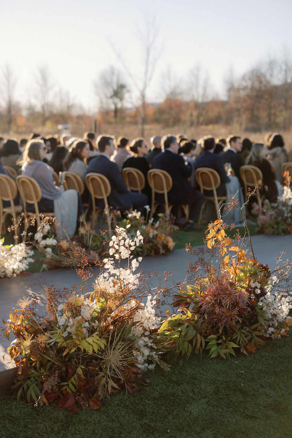 Guests Seated at Wedding Ceremony Next to White and Green Flower Decor
