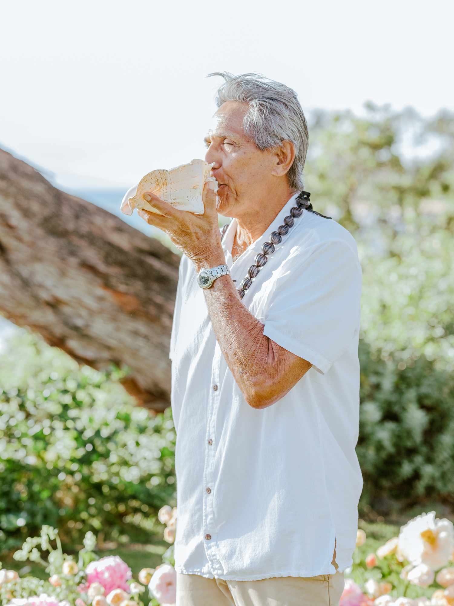 Man Blowing Conch Shell During Hawaiian Wedding Ceremony