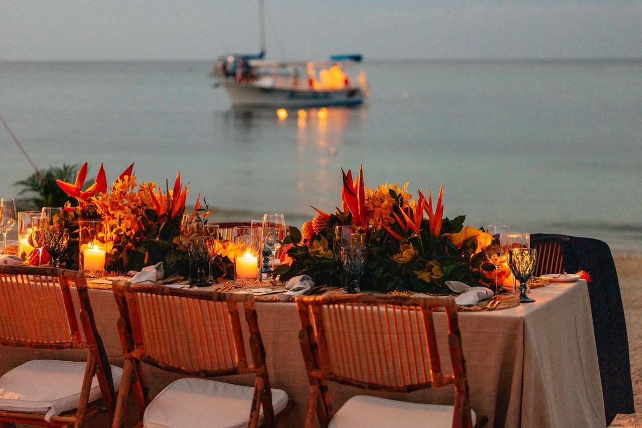 Small Reception Table on Beach With Tropical Flower Decor, Candles, and View of Ocean