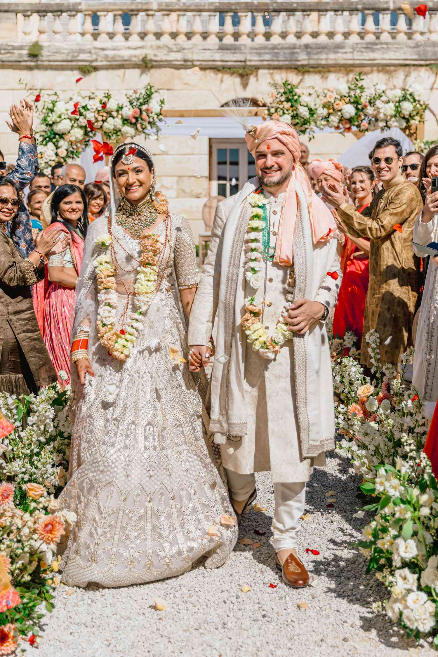 bride and groom leaving ceremony holding hands in traditional Indian wedding attire