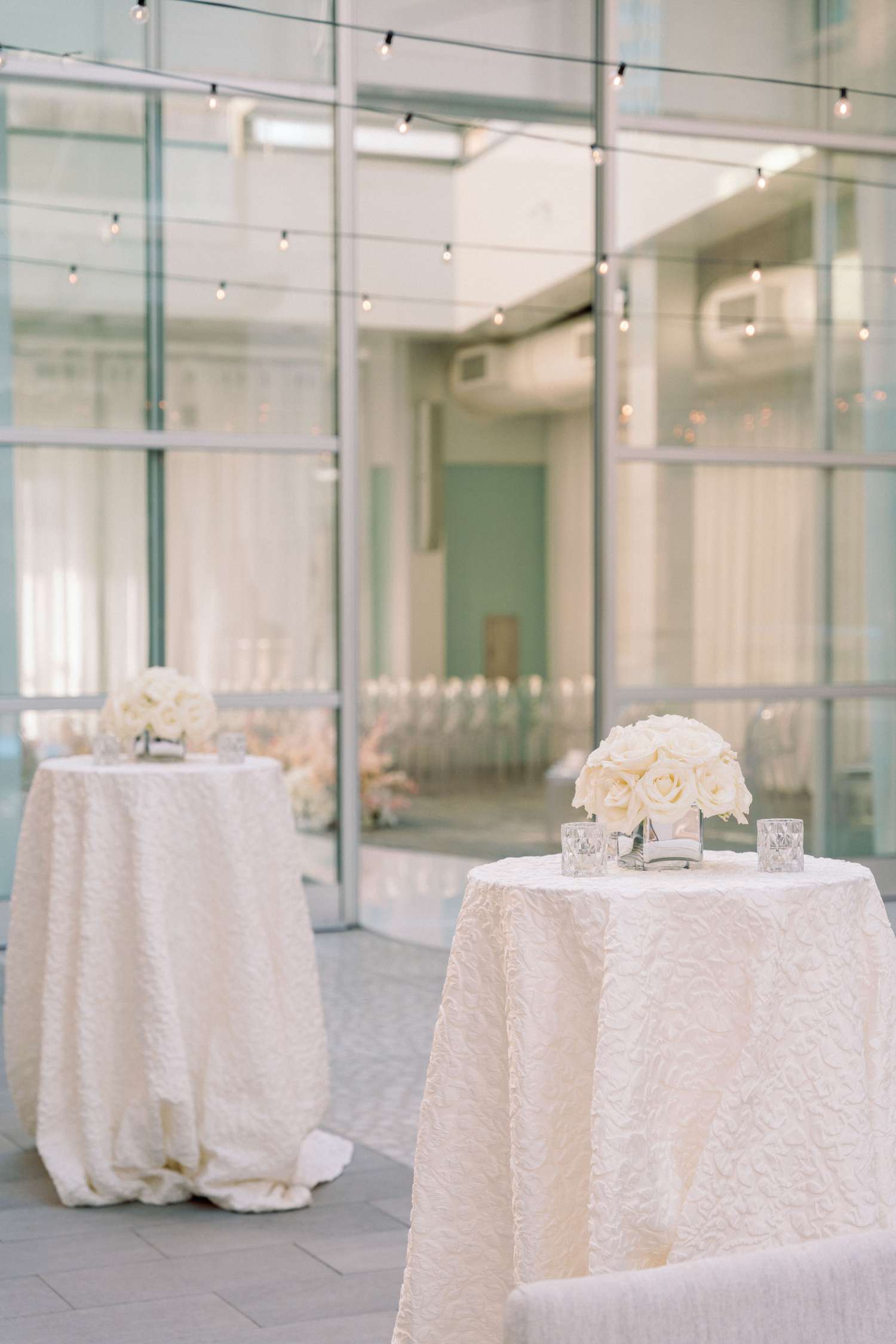 two white cocktail tables with flowers in the center