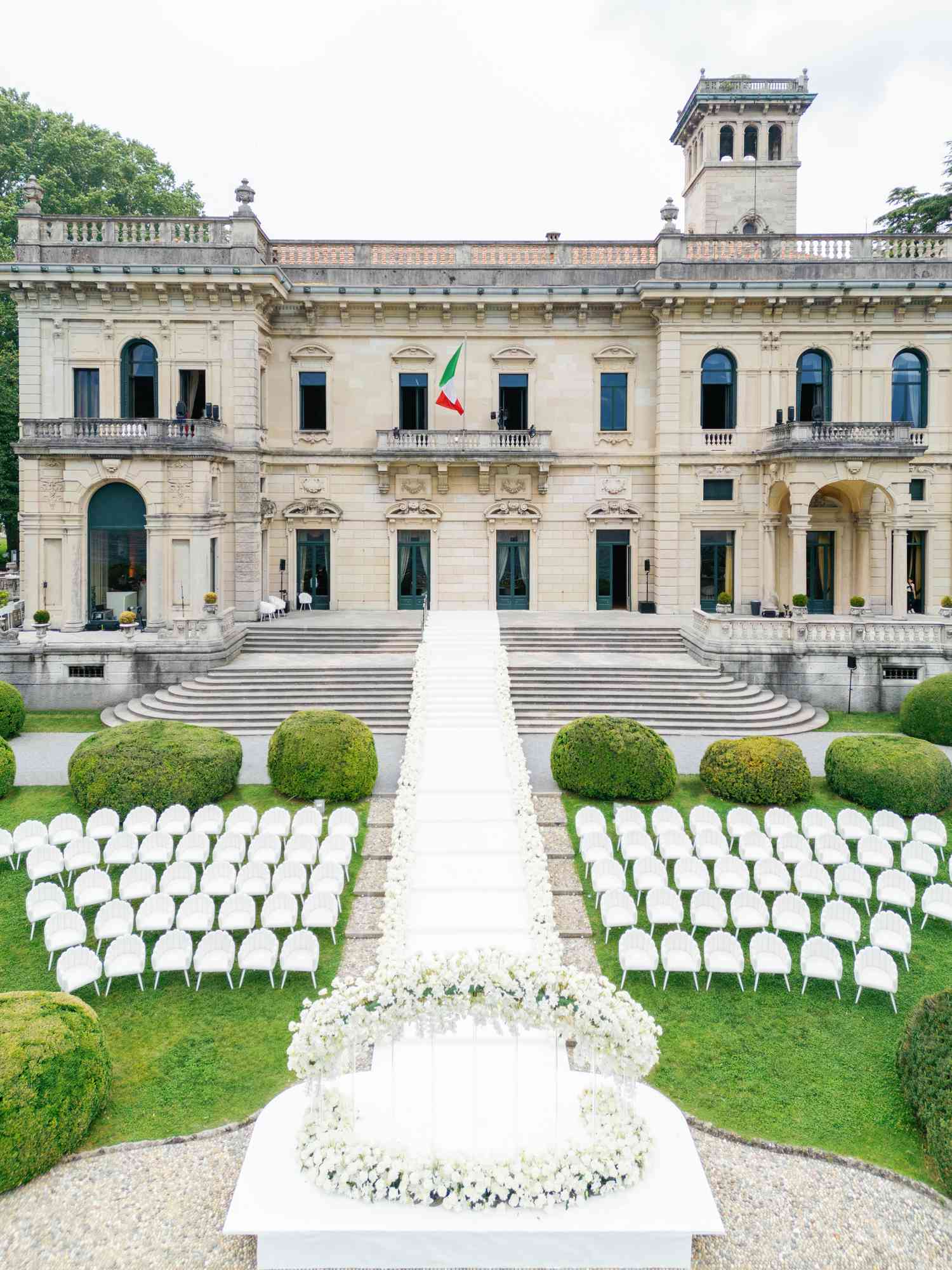 All White Wedding Ceremony Flower, Chair, and Aisle Decor in Courtyard of Italian Villa