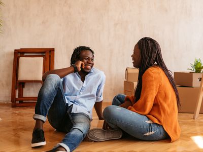 young couple talking while sitting on floor of their new apartment