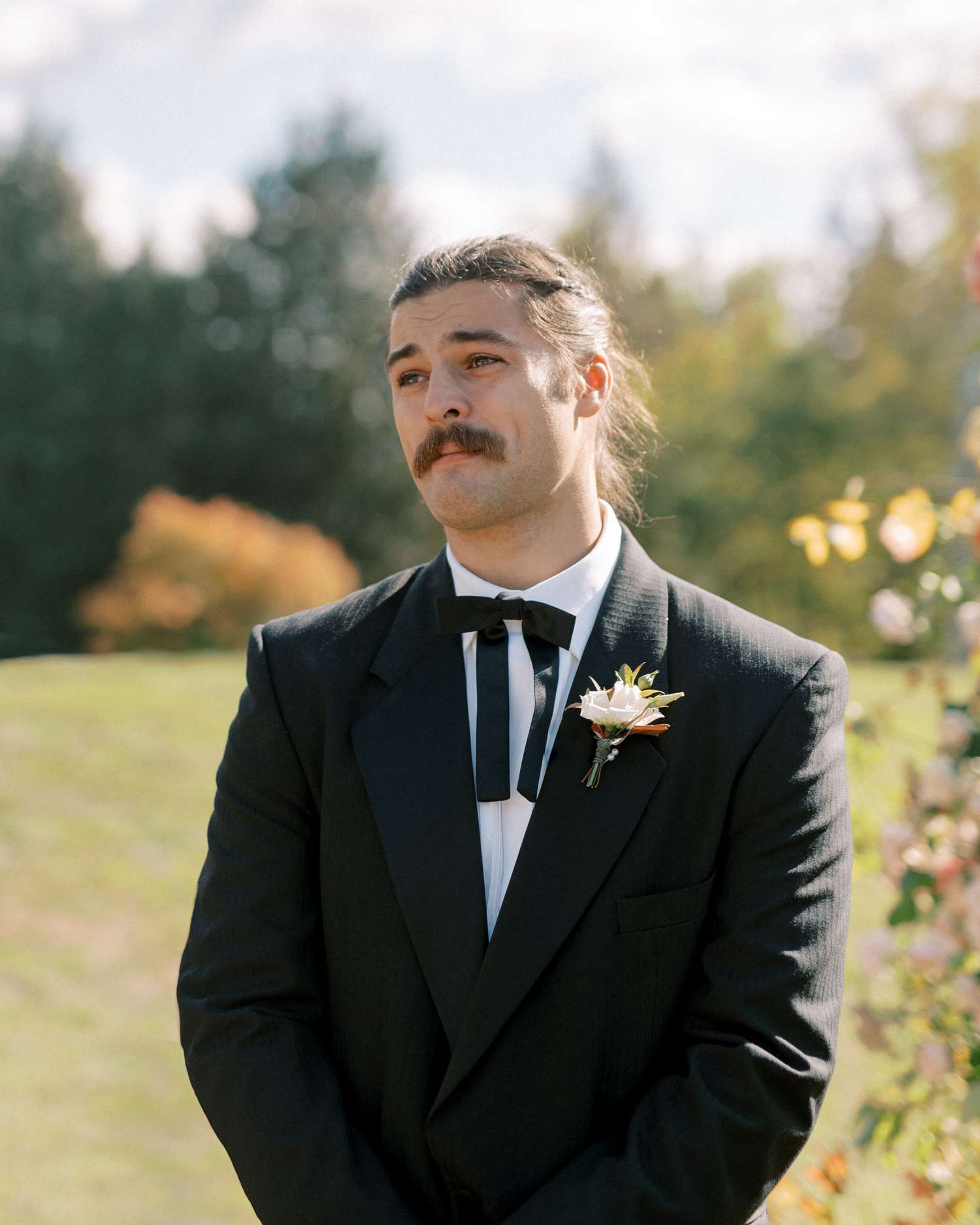 Groom in Black Tuxedo With Ribbon Bow Tie Standing at Altar