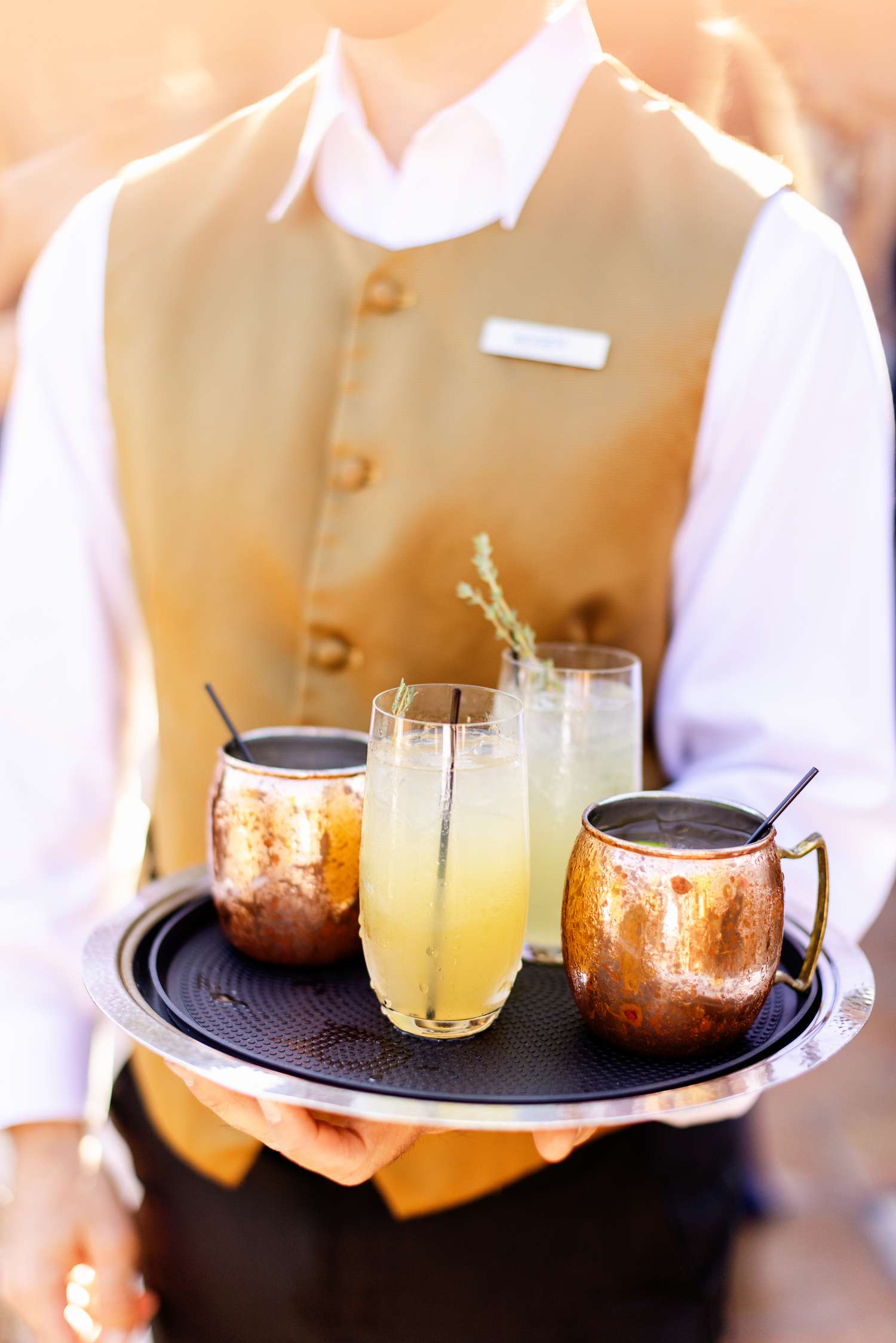 Server in Orange Vest Holding Tray of Cocktails