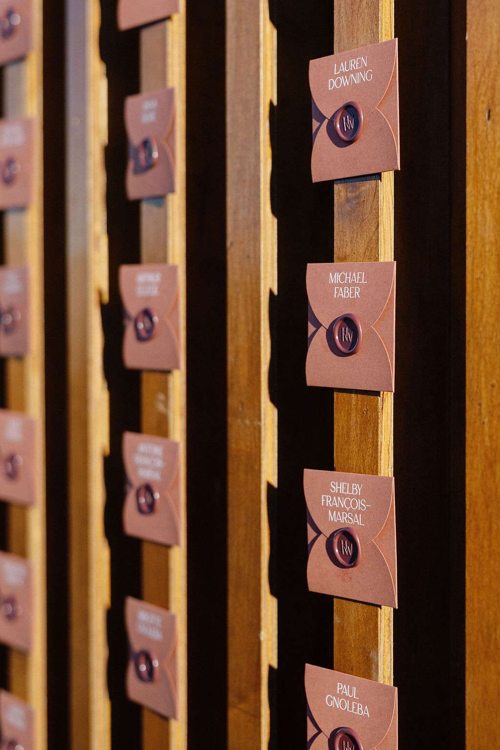 Wedding Reception Seating Chart in Orange Envelopes on Wooden Panels
