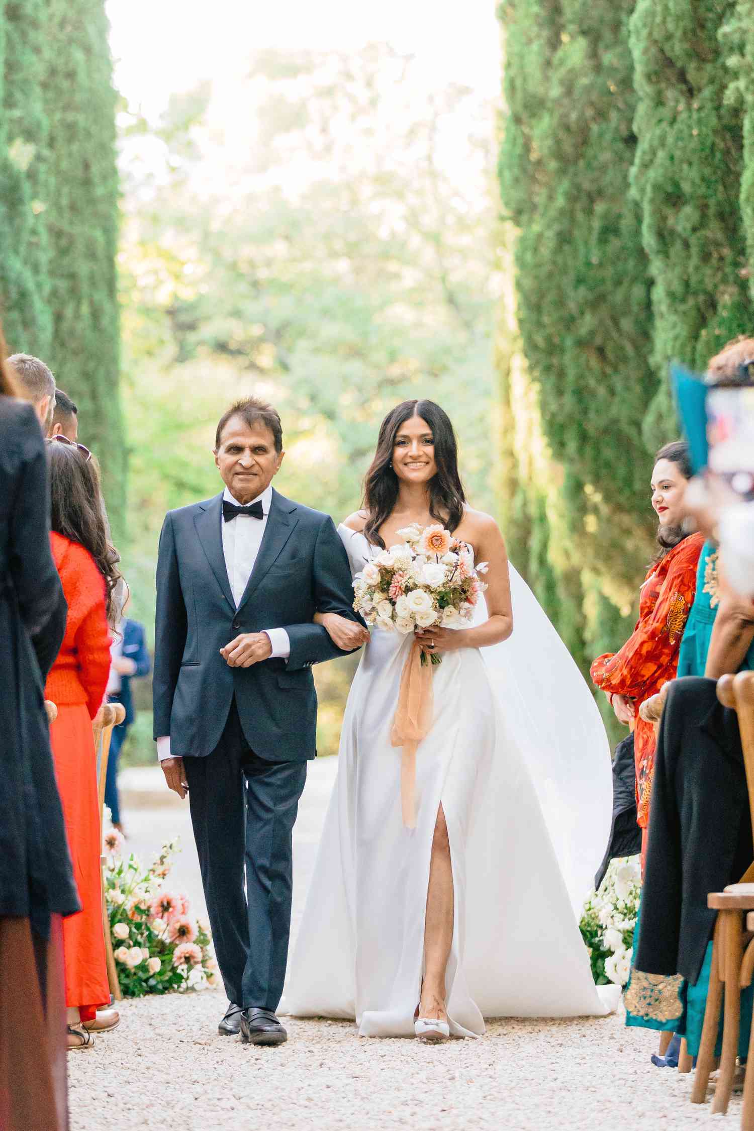 bride in traditional white wedding dress walking down aisle with father