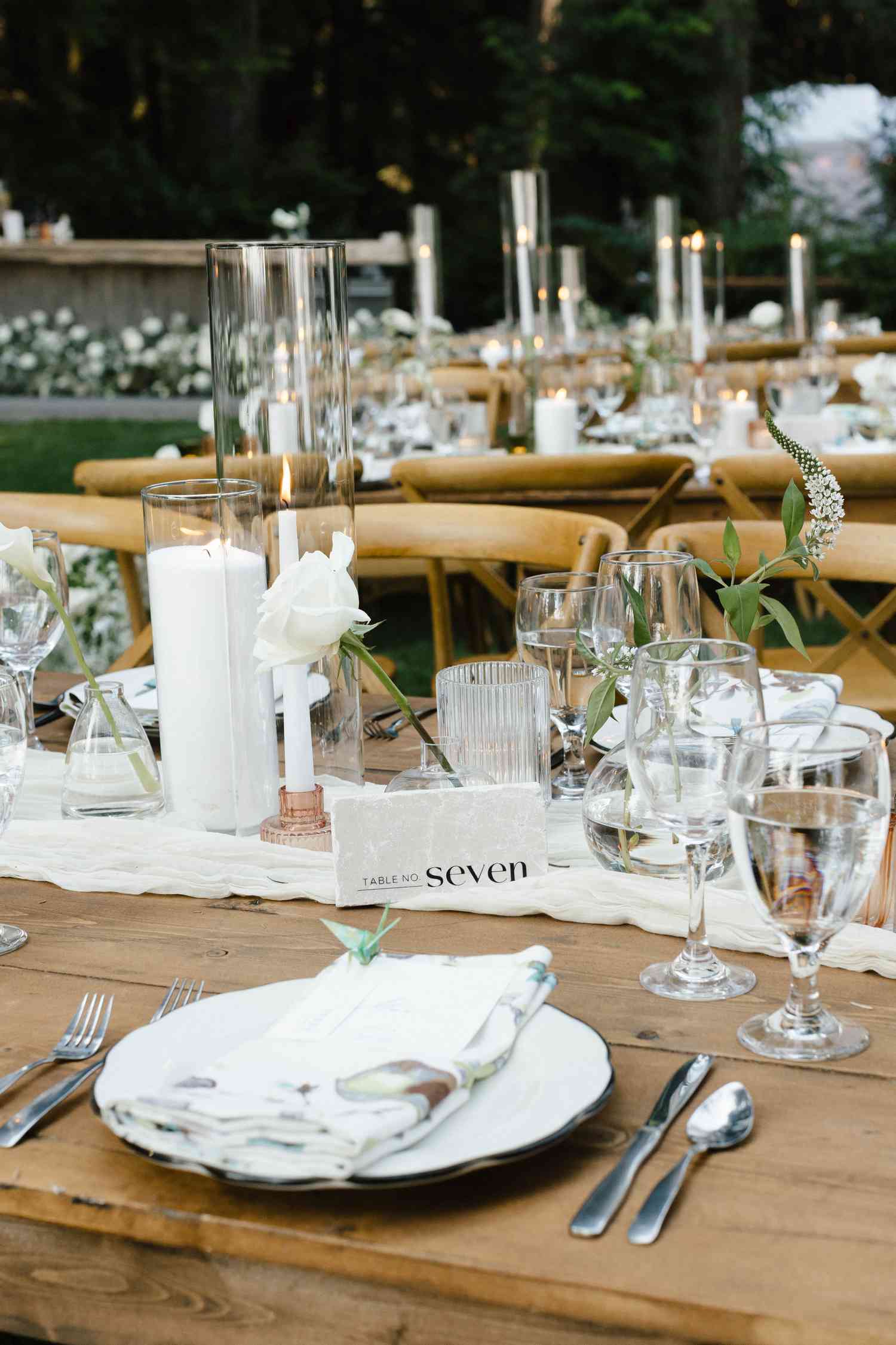 Wedding Reception Tables With White Gauze Runners, White Plates, Candles, and Bud Vases