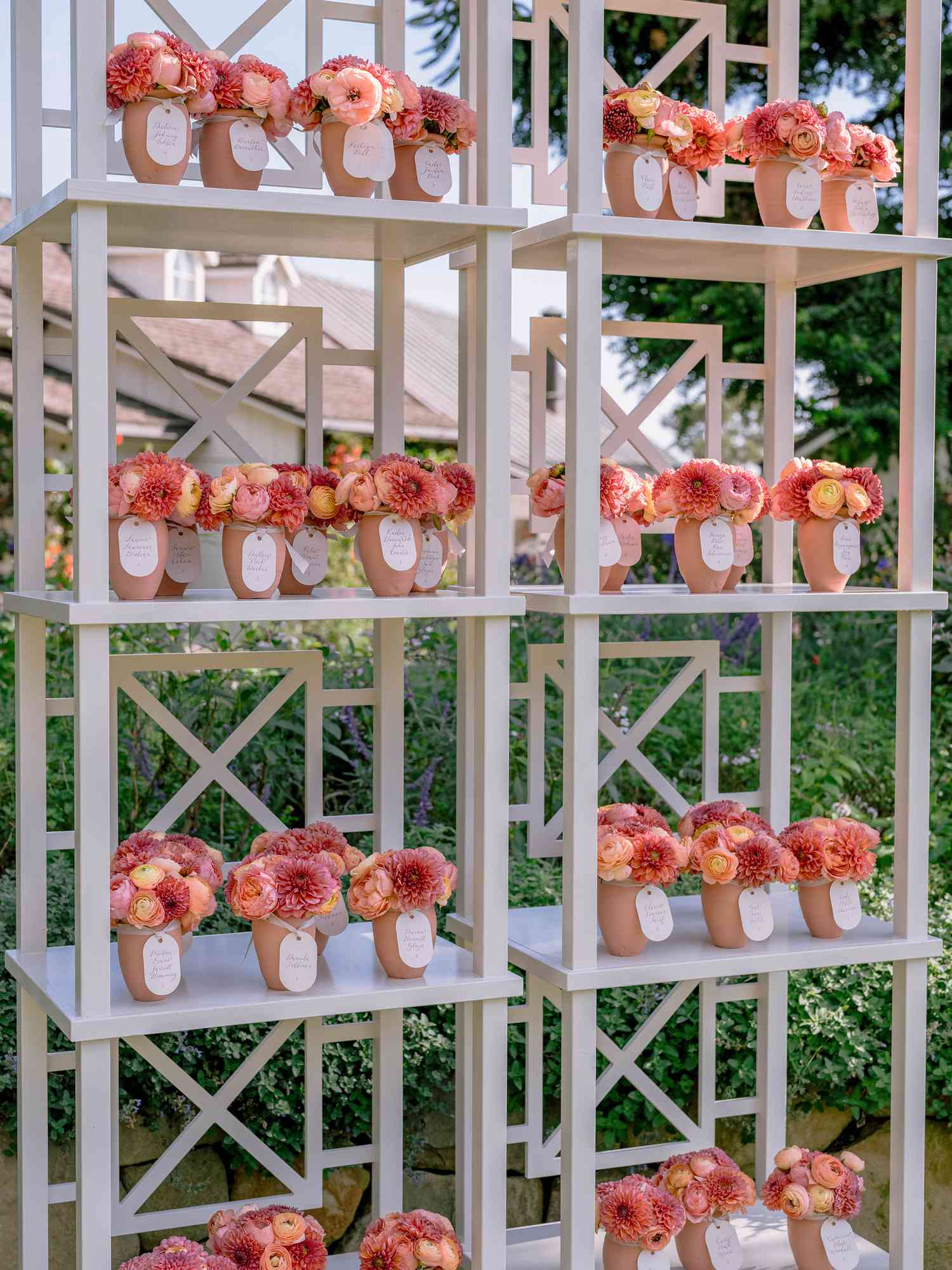 shelves with mini flower bouquets in clay vases with name tags attached on them