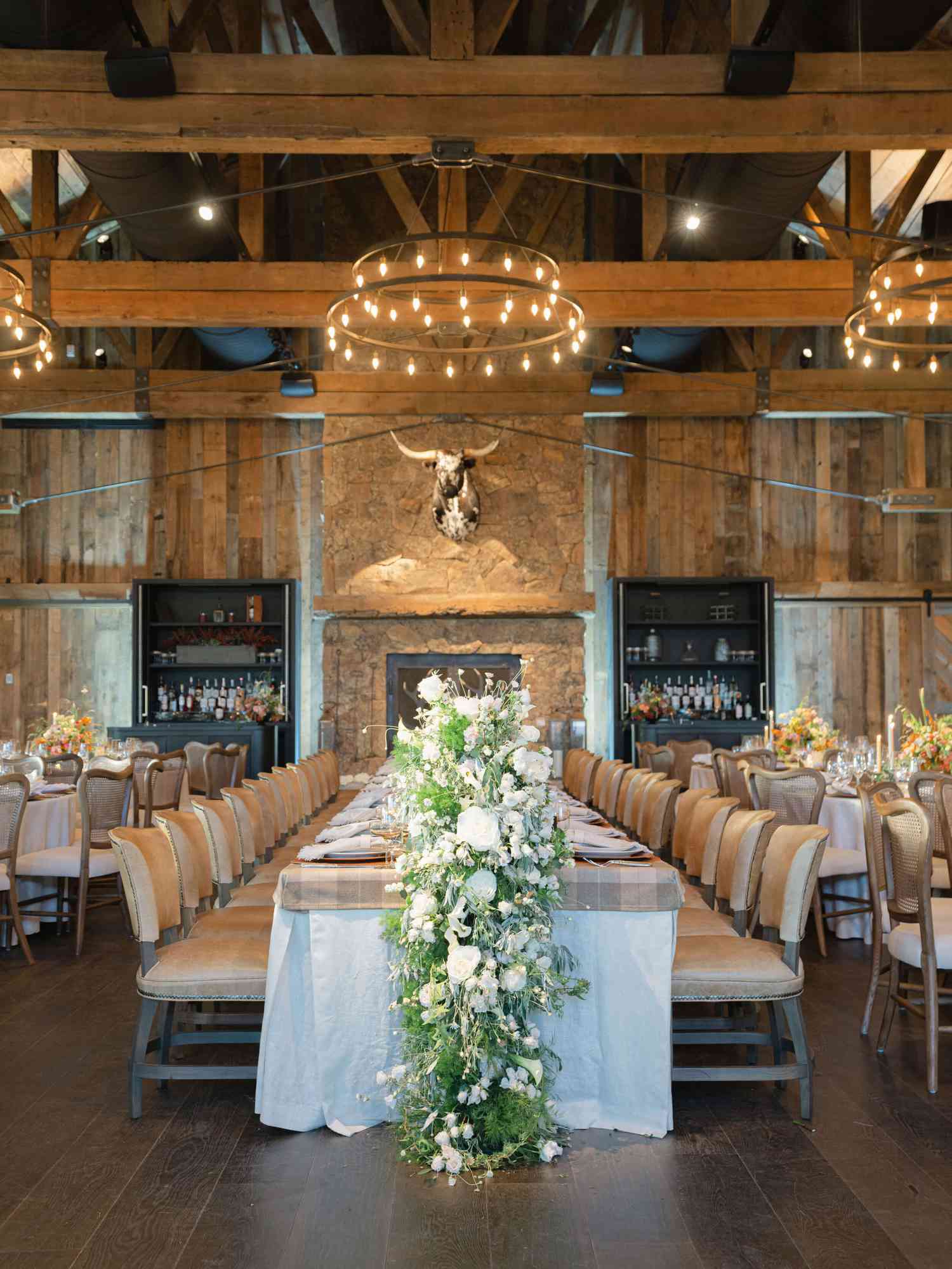 wedding reception with white and green floral garland and chandeliers overhead