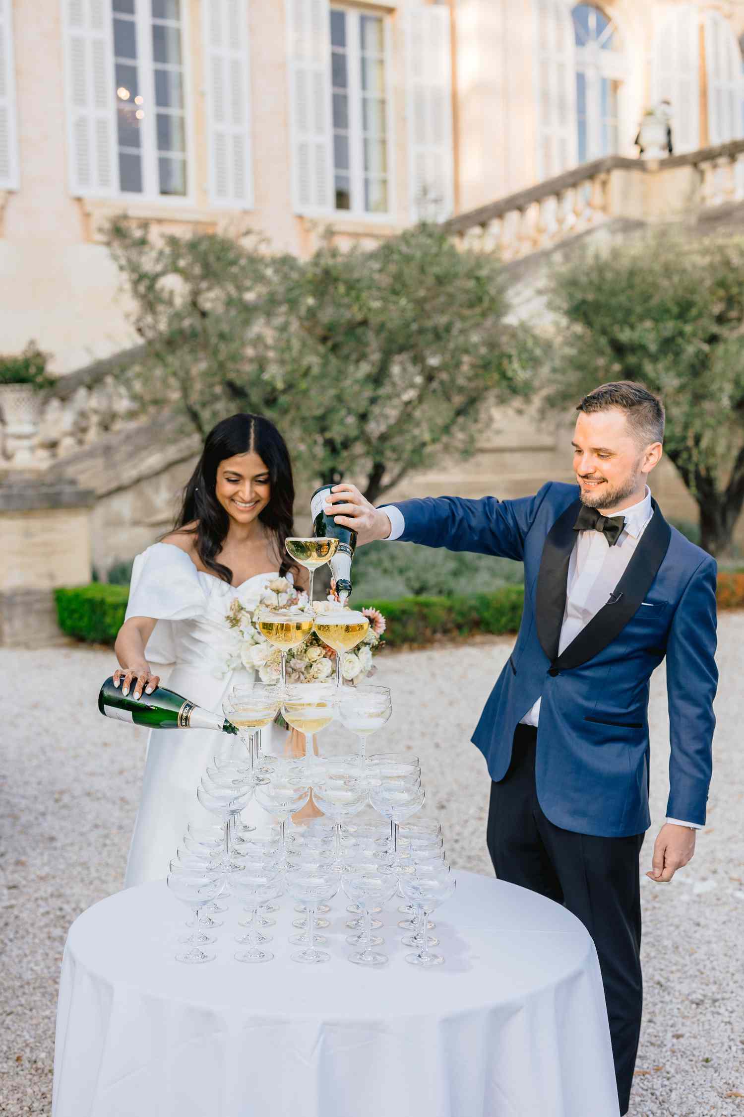 bride and groom pour champagne in cup tower