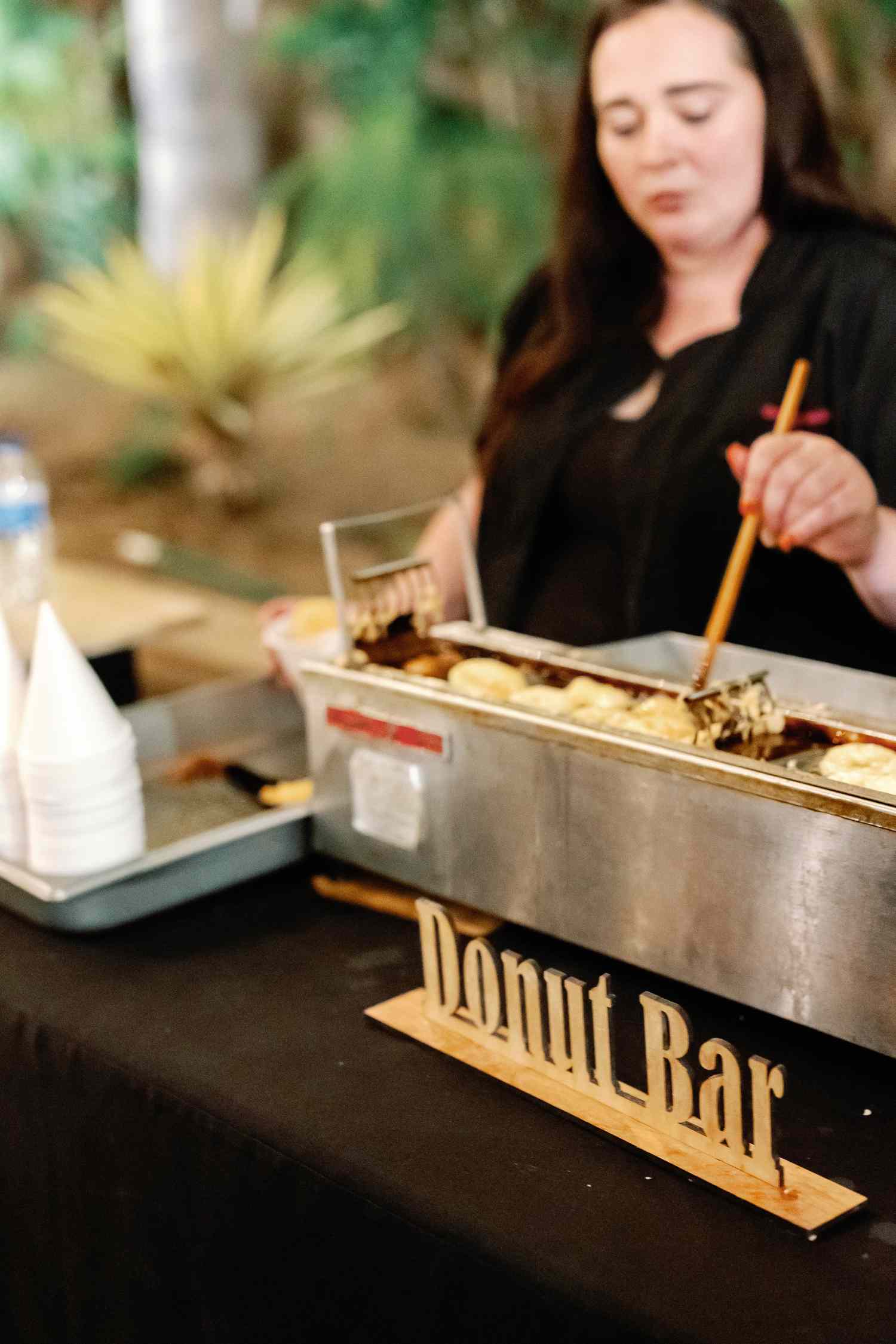 Woman in Black Uniform Making Donuts at Donut Bar at Wedding Reception