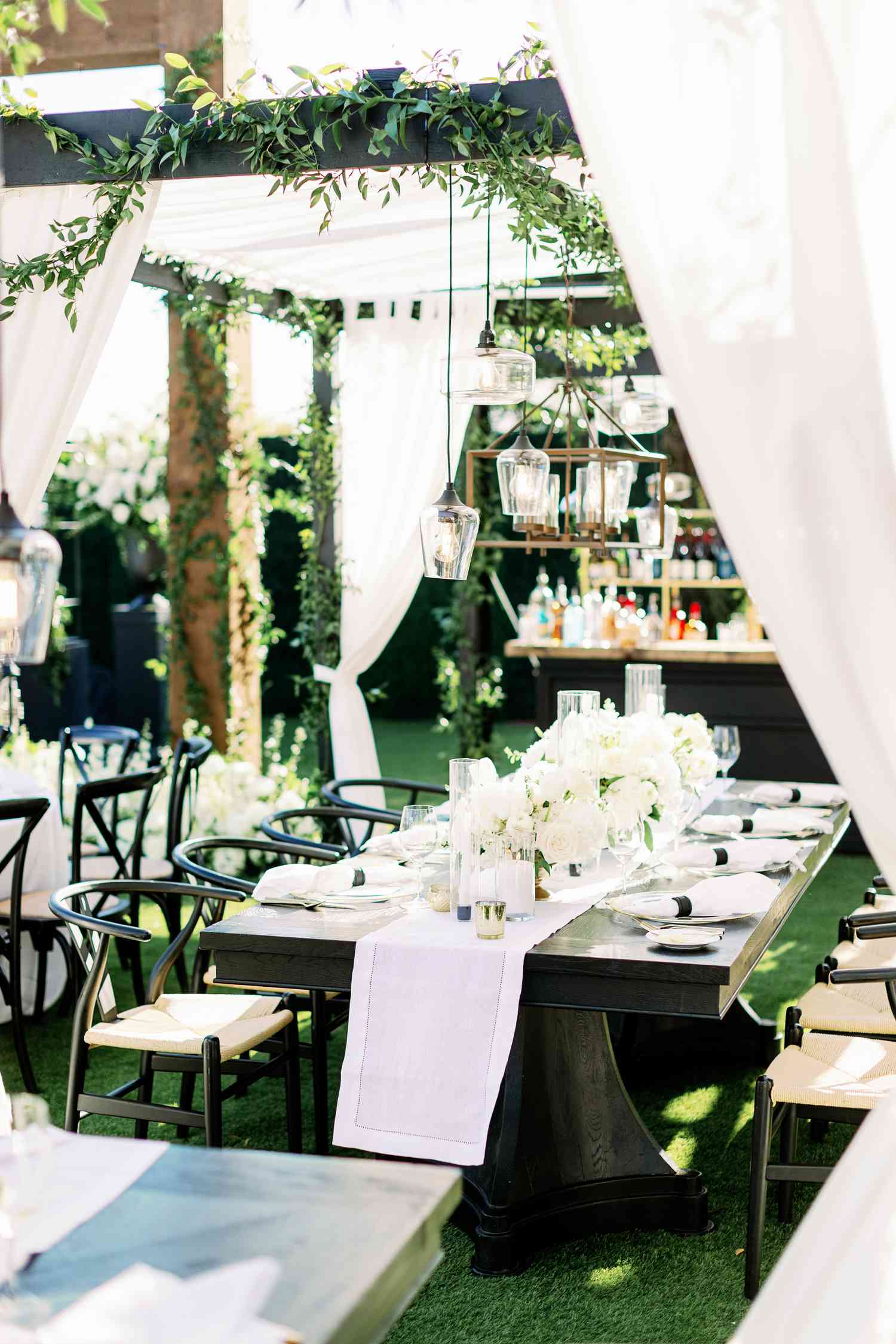 Black Wedding Table With White Runner, White Centerpieces, and Pergola With Draping