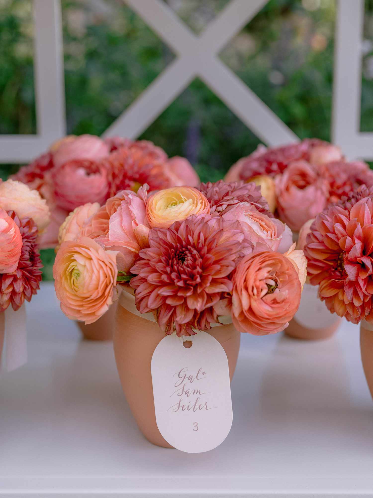 flower bouquet in clay vase with a white name tag with names and a table number written