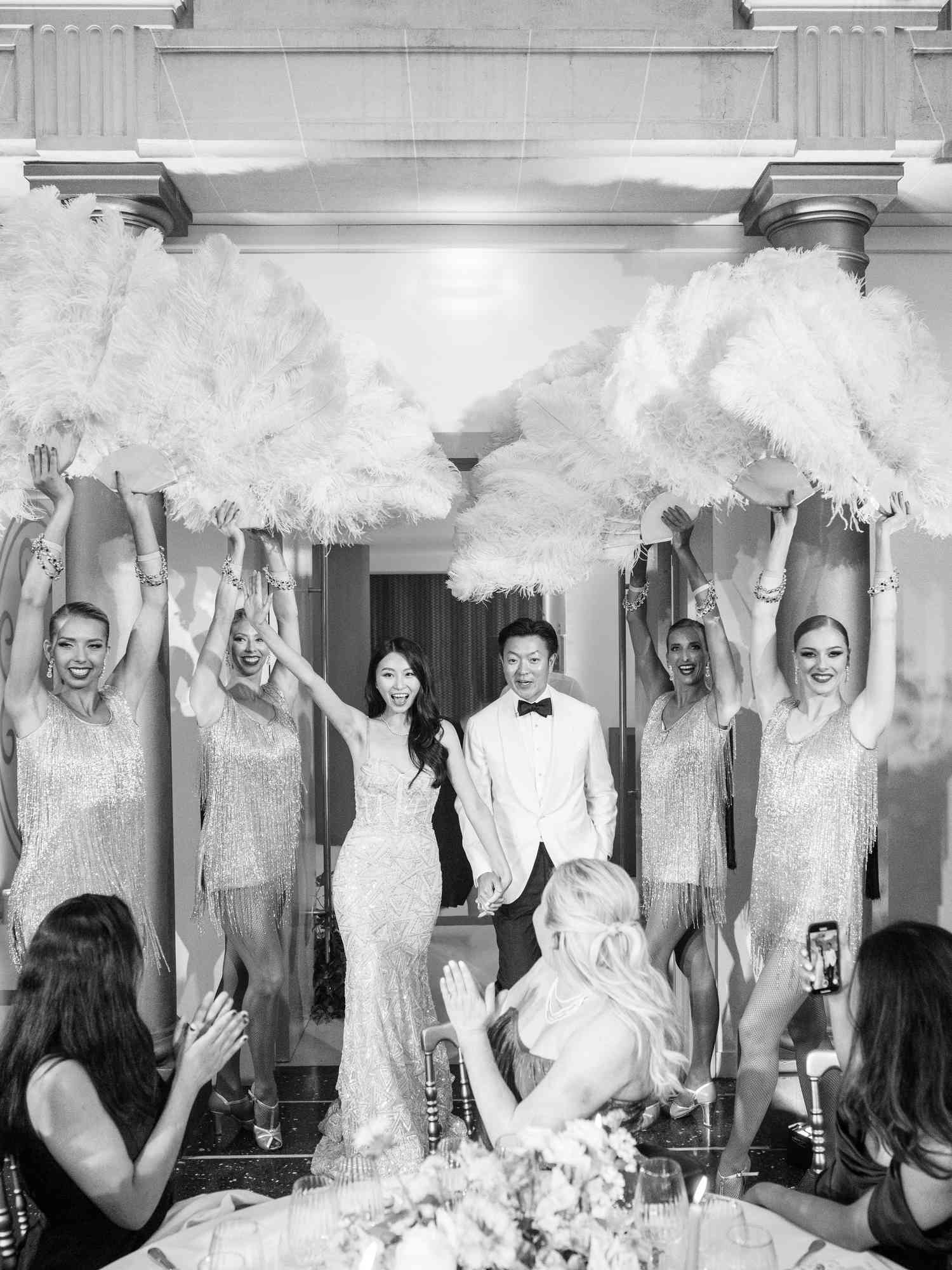 Bride and groom enter reception behind cabaret dancer fans