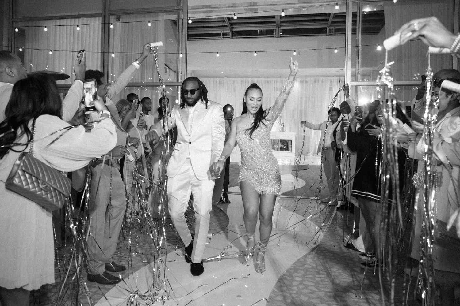 black and white photo of bride and groom dancing down aisle