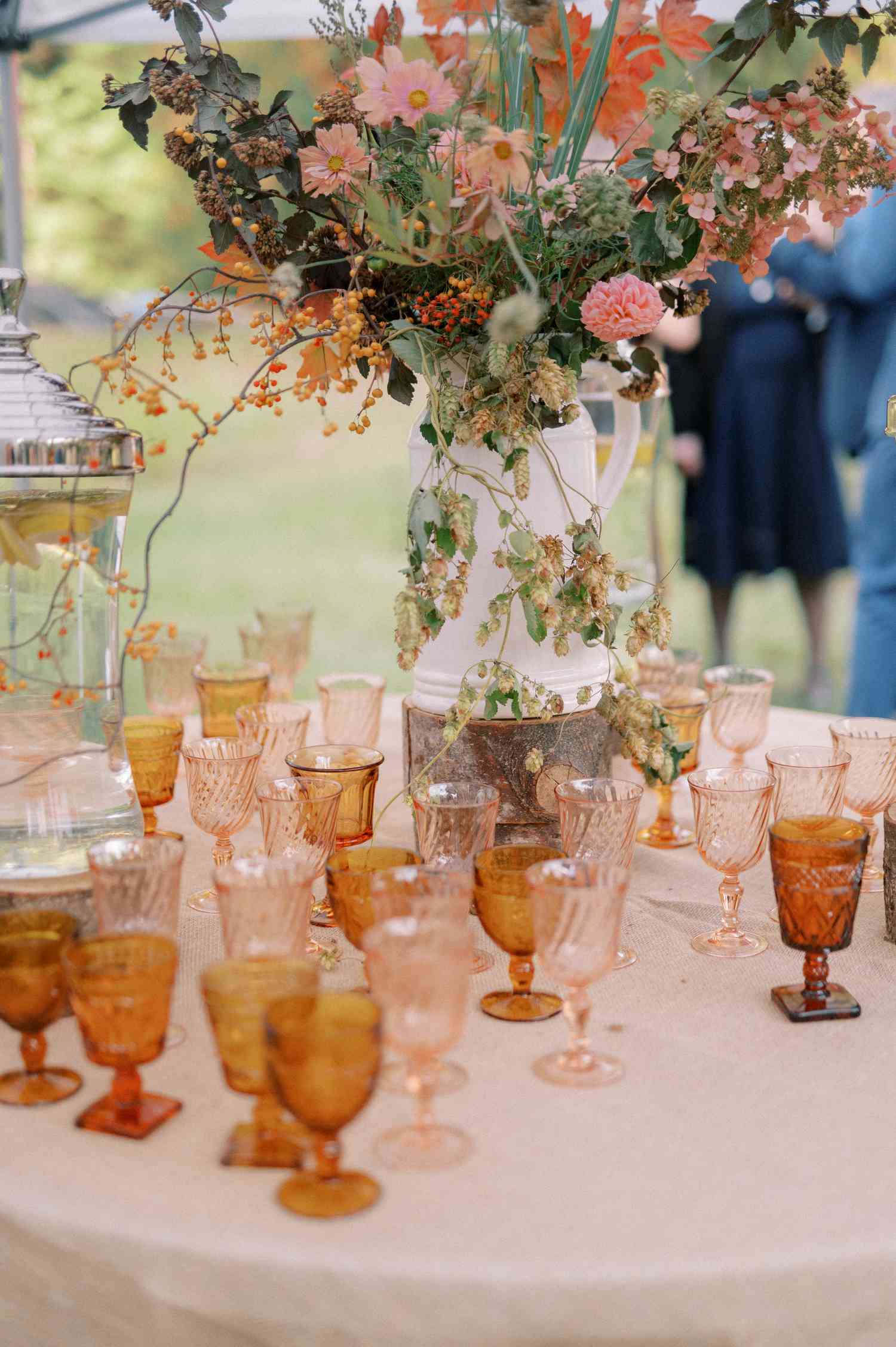 Colorful Cocktail Glasses on Table Next to Colorful Flowers in White Vase