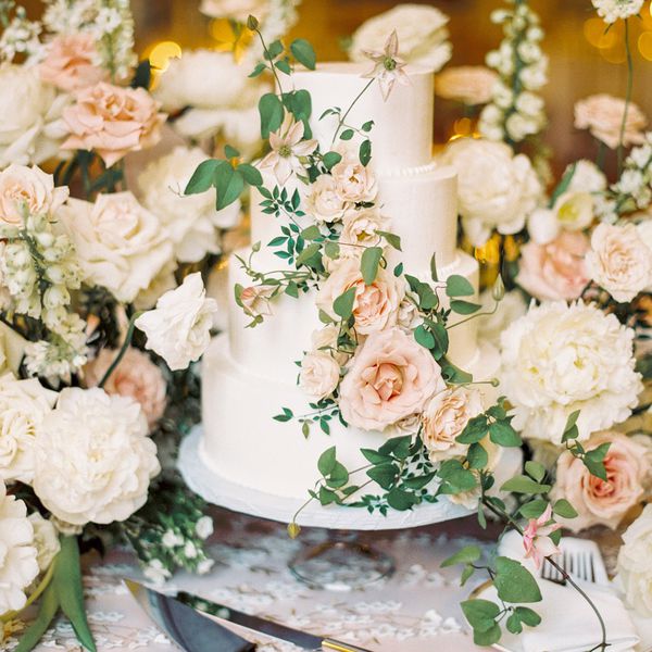 A white wedding cake covered in pink and white roses.
