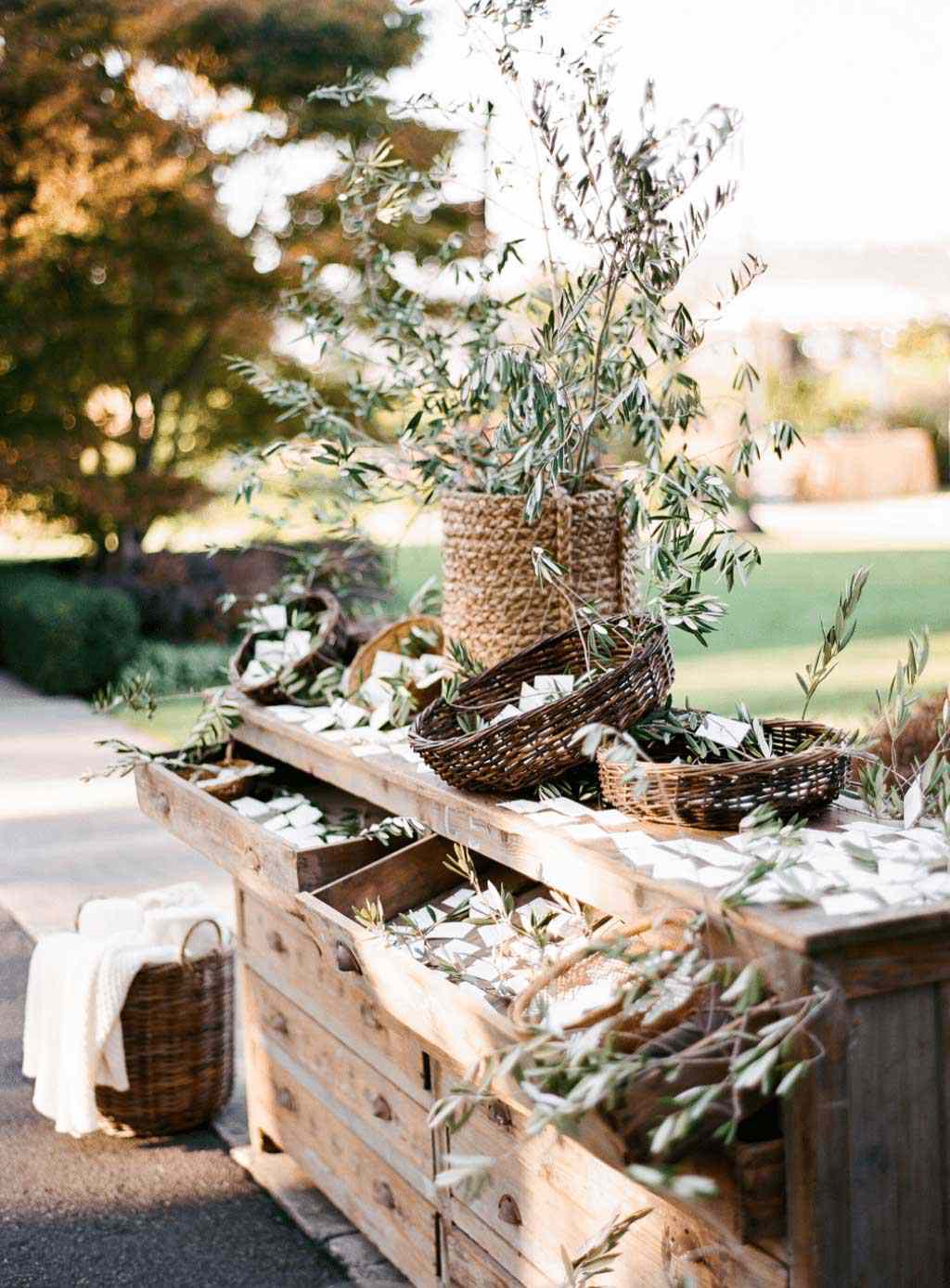 Rustic Escort card display on vintage dresser with overflowing baskets of olive branches