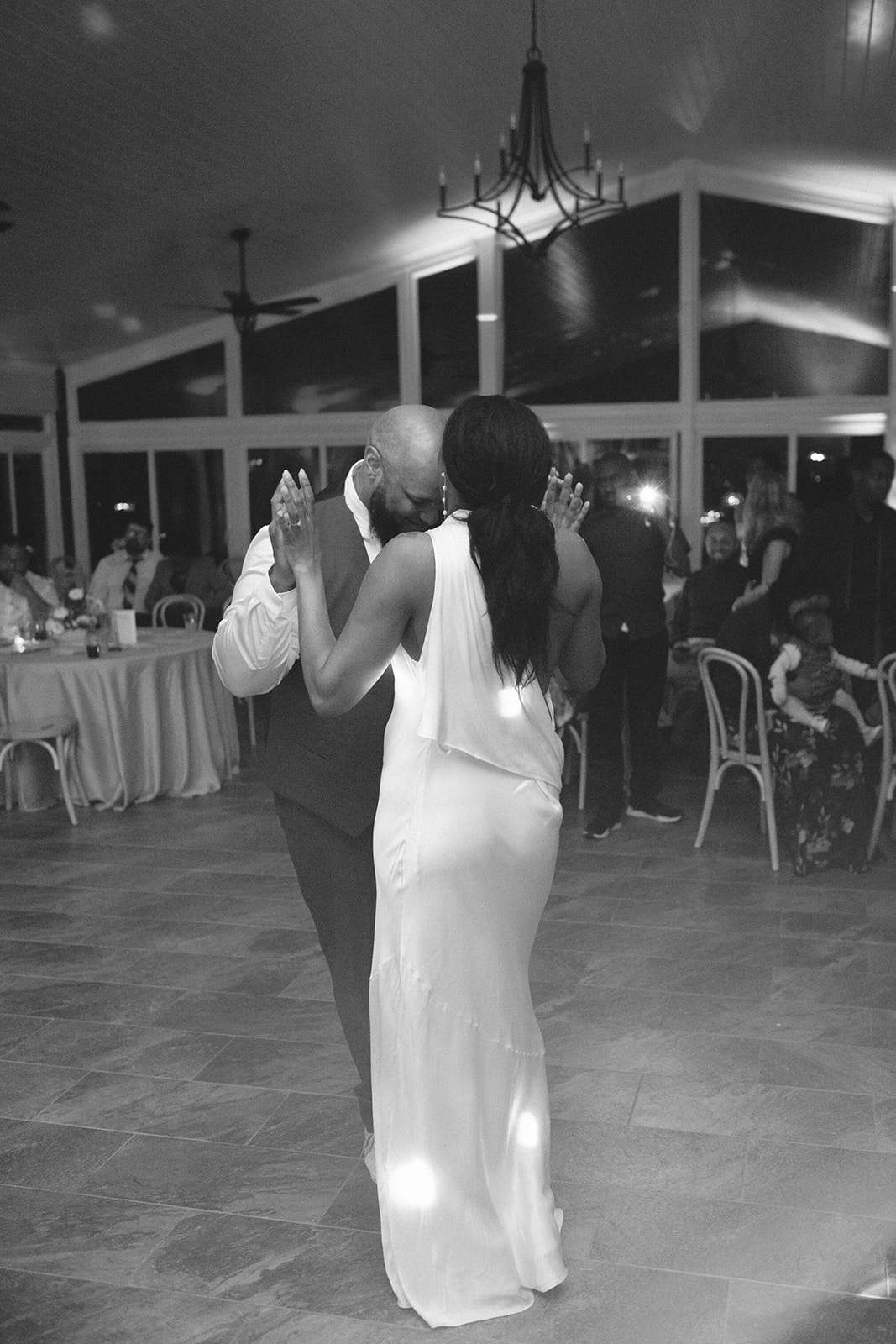 Black and White Image of Bride in Silk Dress Dancing With Groom in Suit on Reception Dance Floor
