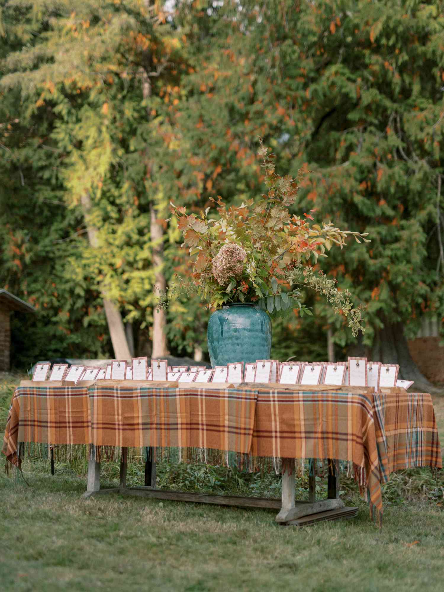 Seating Chart on Plaid Table With Large Plant Centerpiece in Blue Vase