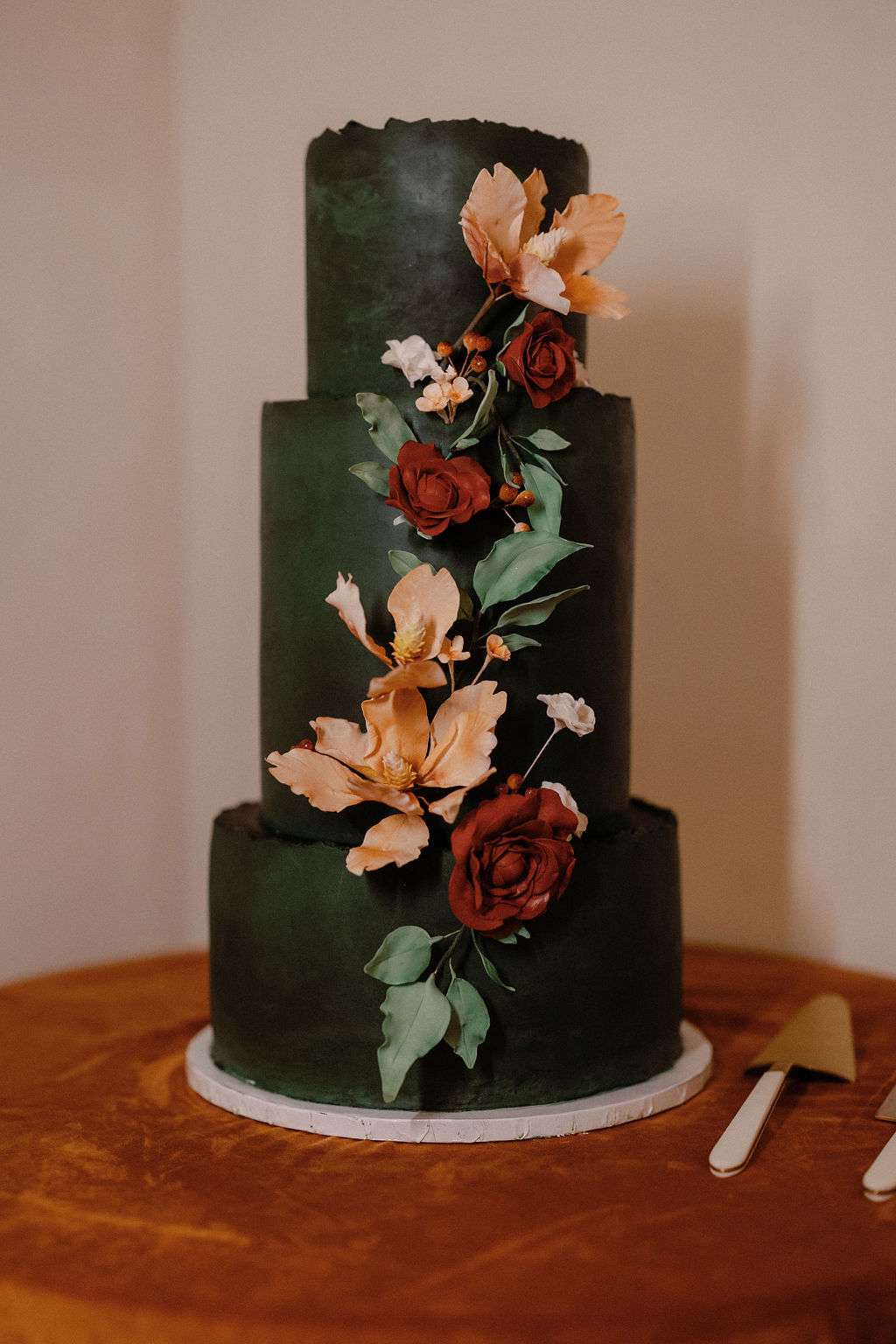 3 Tier Dark Green Wedding Cake With Red and Orange Flowers on Wooden Table